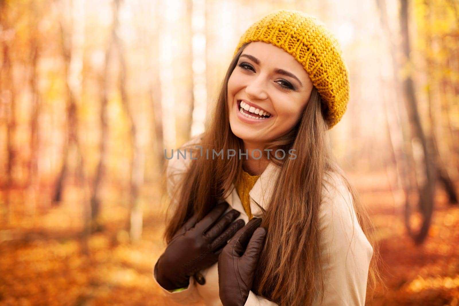 Young woman wearing autumn clothes laughing in park