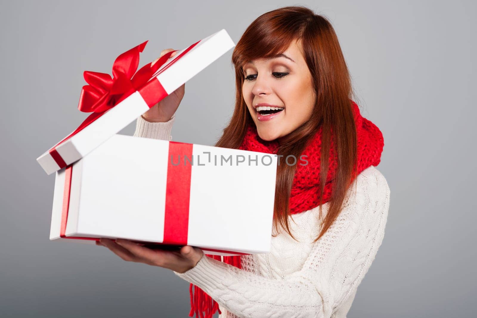 Surprised young woman peeking into the christmas gift