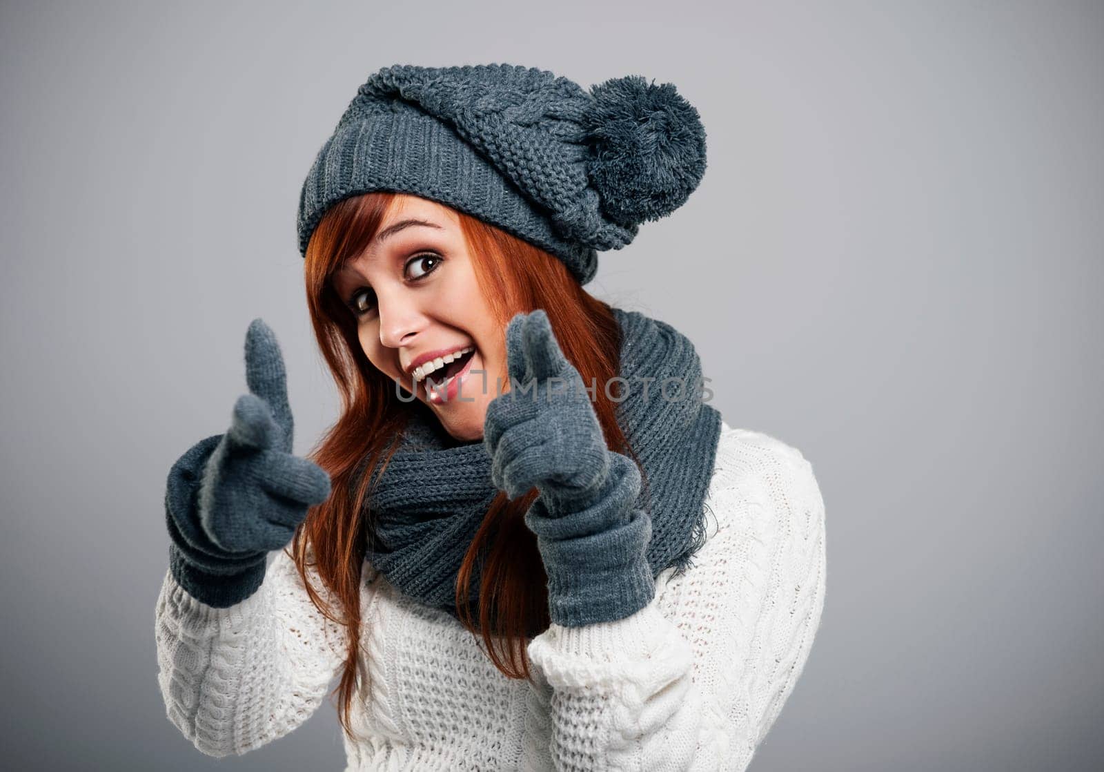 Young woman wearing warm clothes pointing at camera