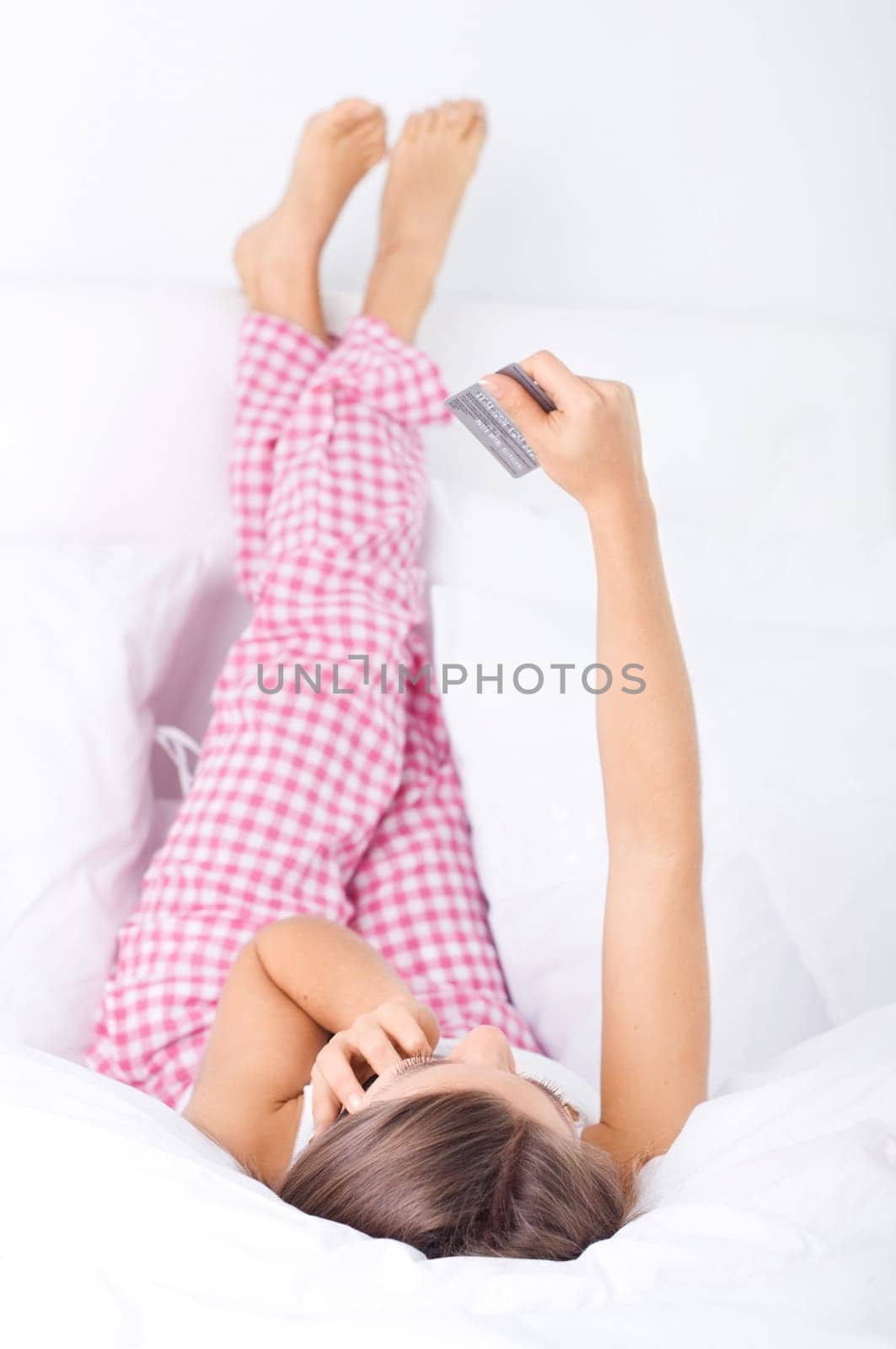 Young woman making shopping over the phone in bed