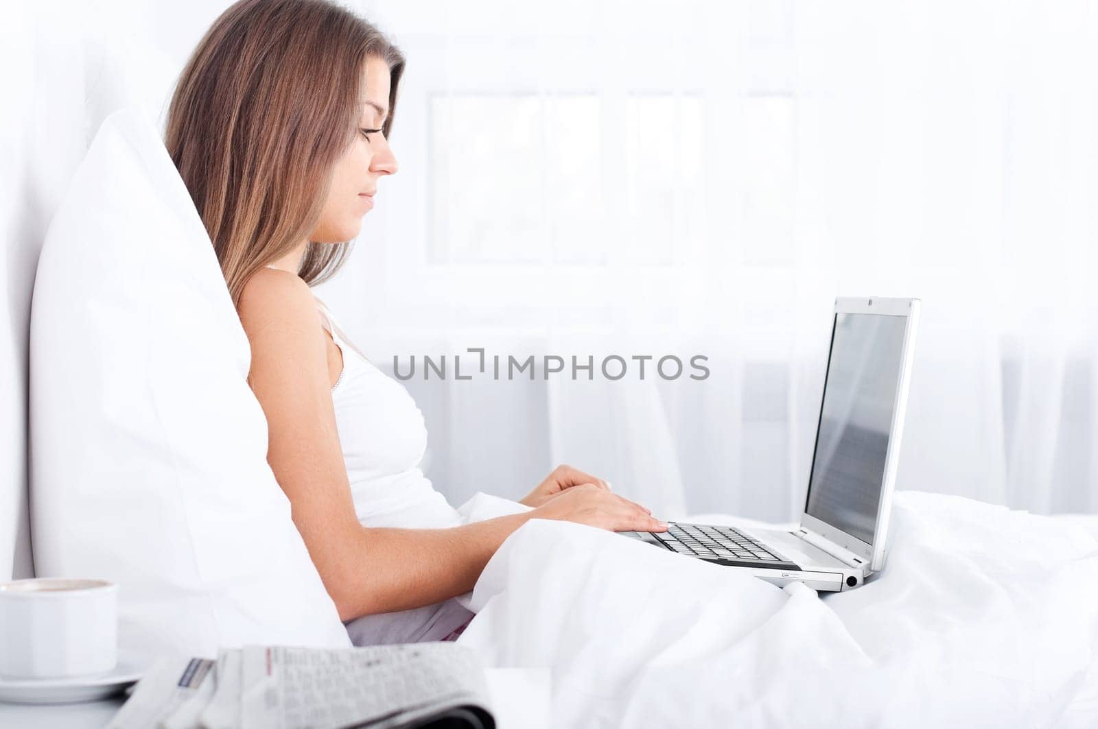 Young woman using laptop in bed