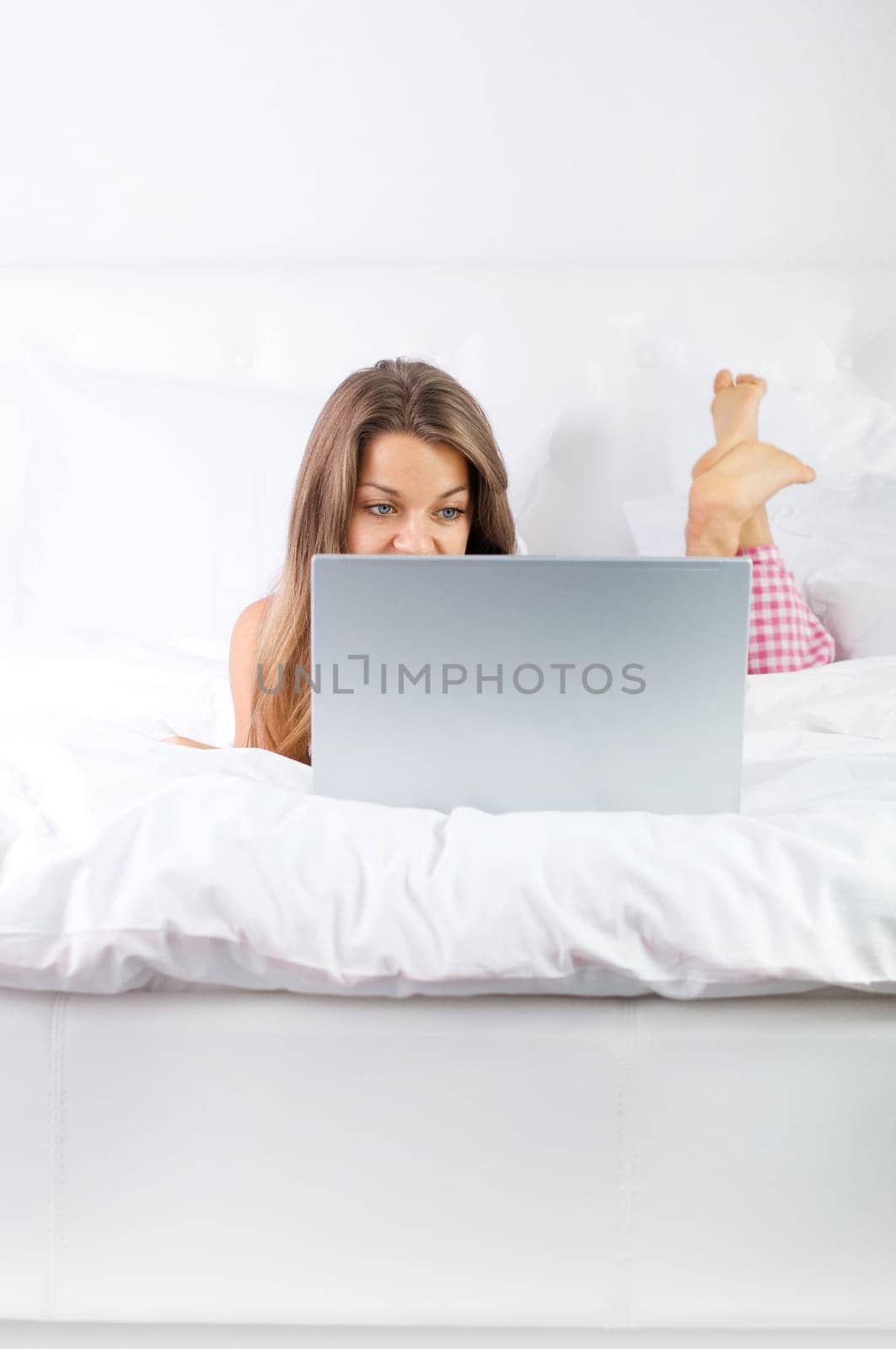Young woman using laptop in bed