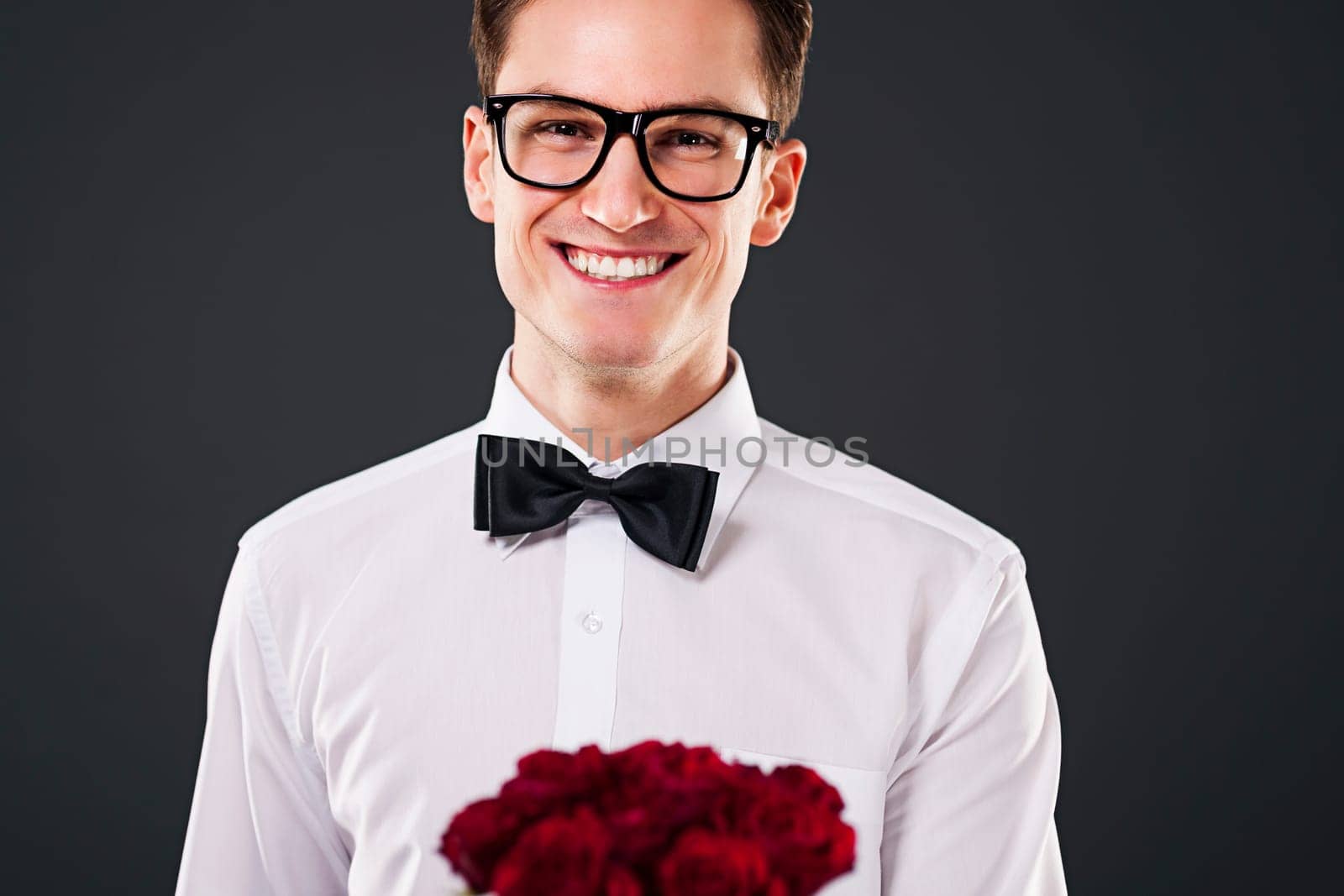 Man wearing on glasses holding bouquet of red roses