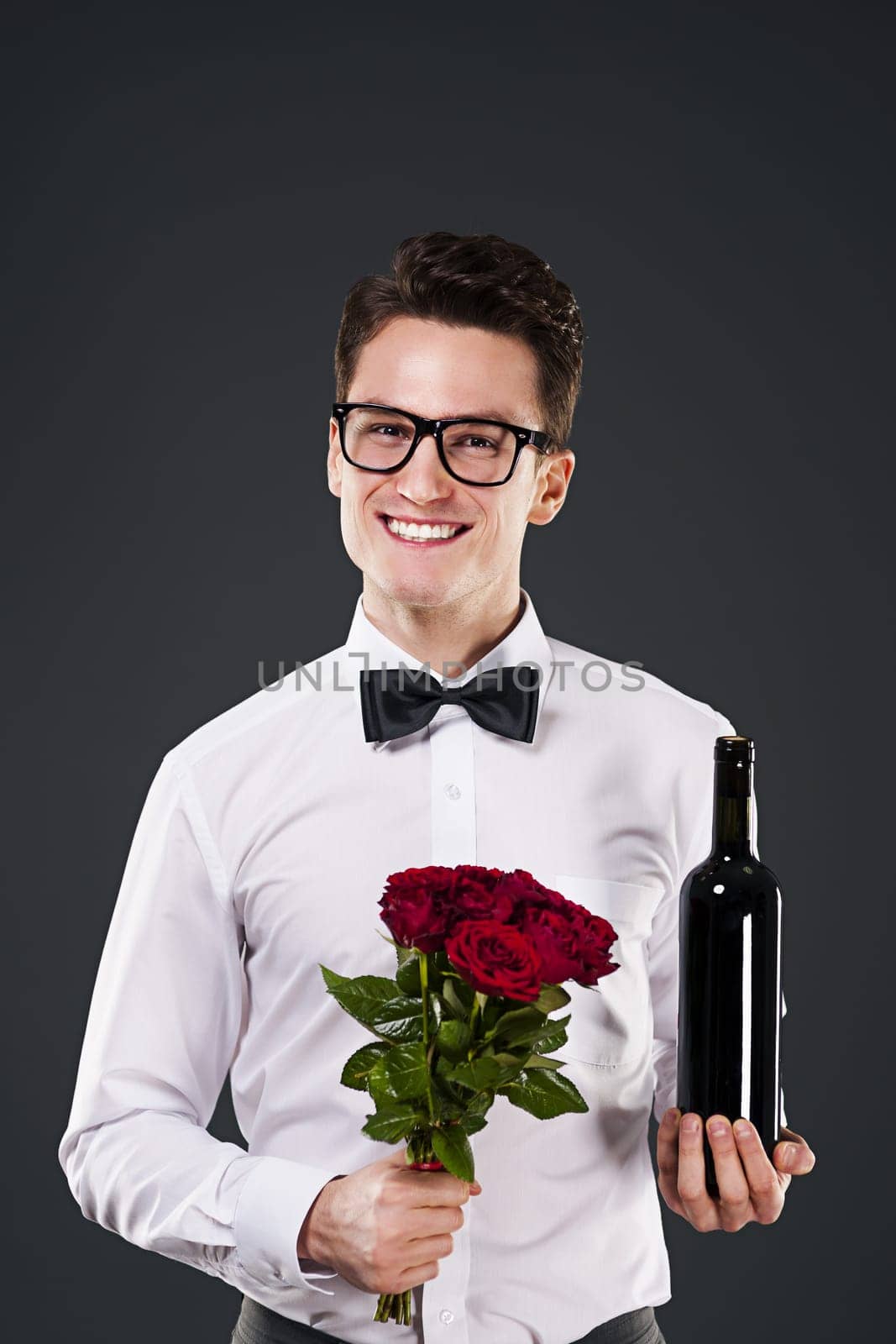 Handsome man with red wine and bouquet of roses