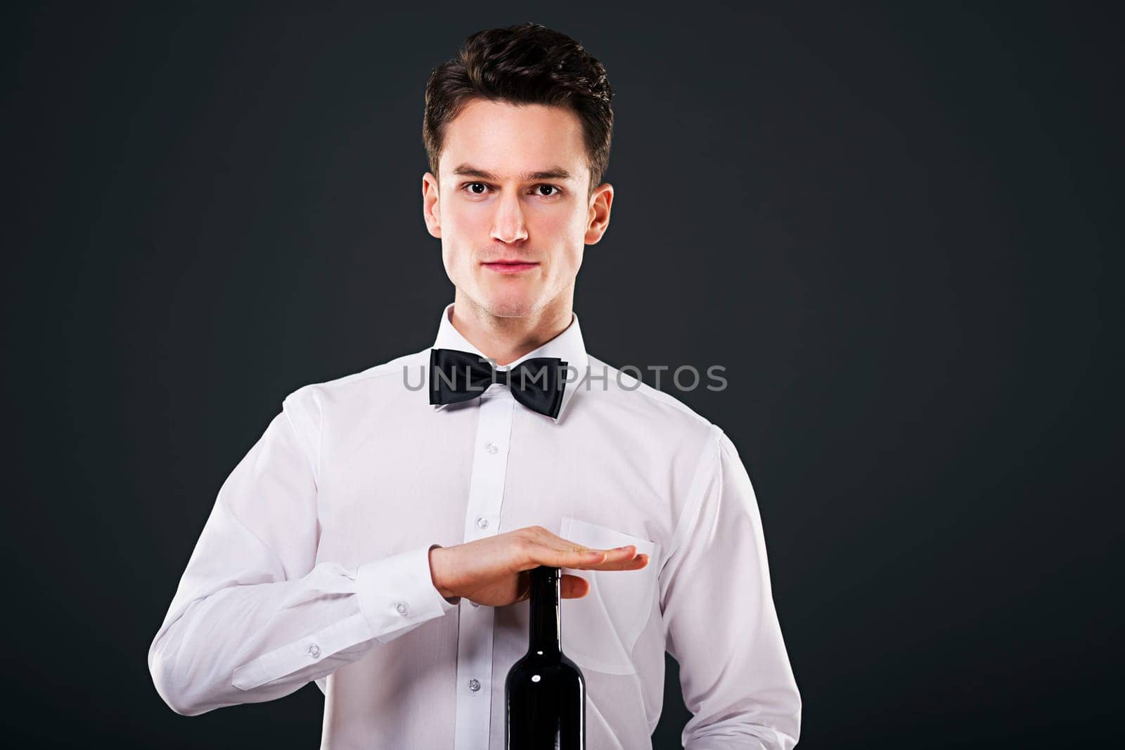 Focused waiter holding a bottle of wine