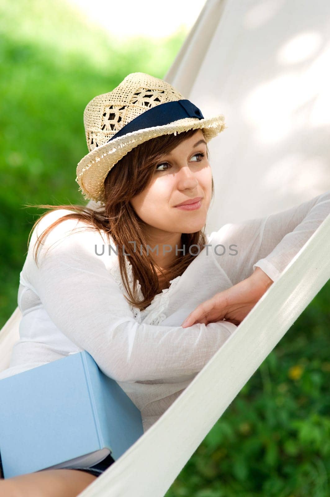 Young woman relaxing in a hammock with book