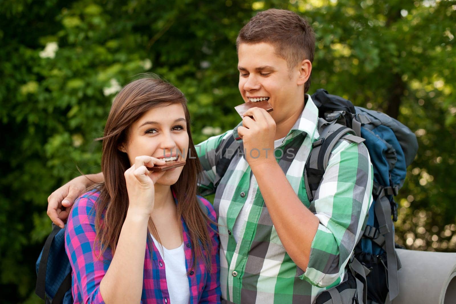 Young couple eating chocolate in forest