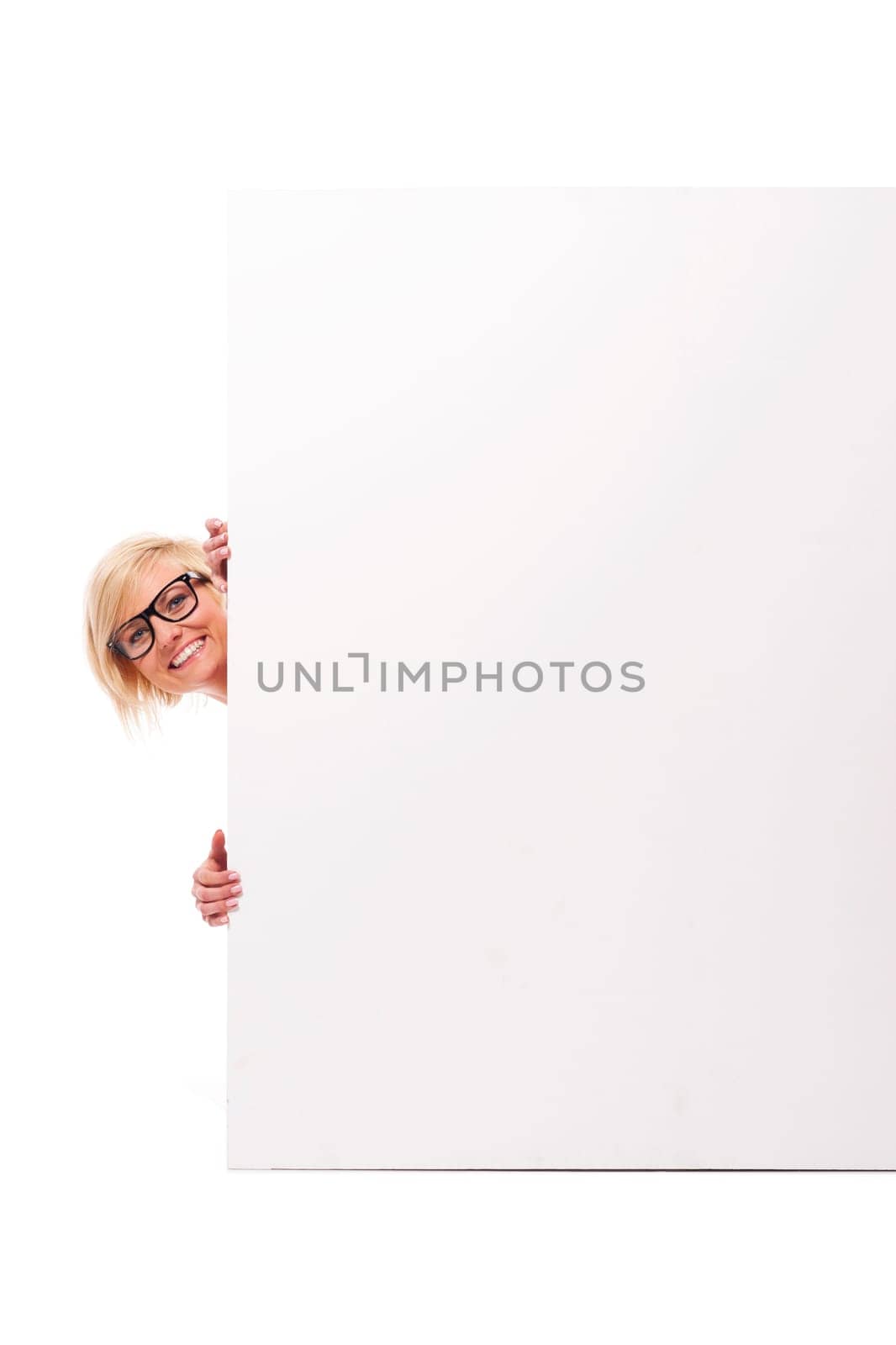 Happy young woman peeking from behind whiteboard