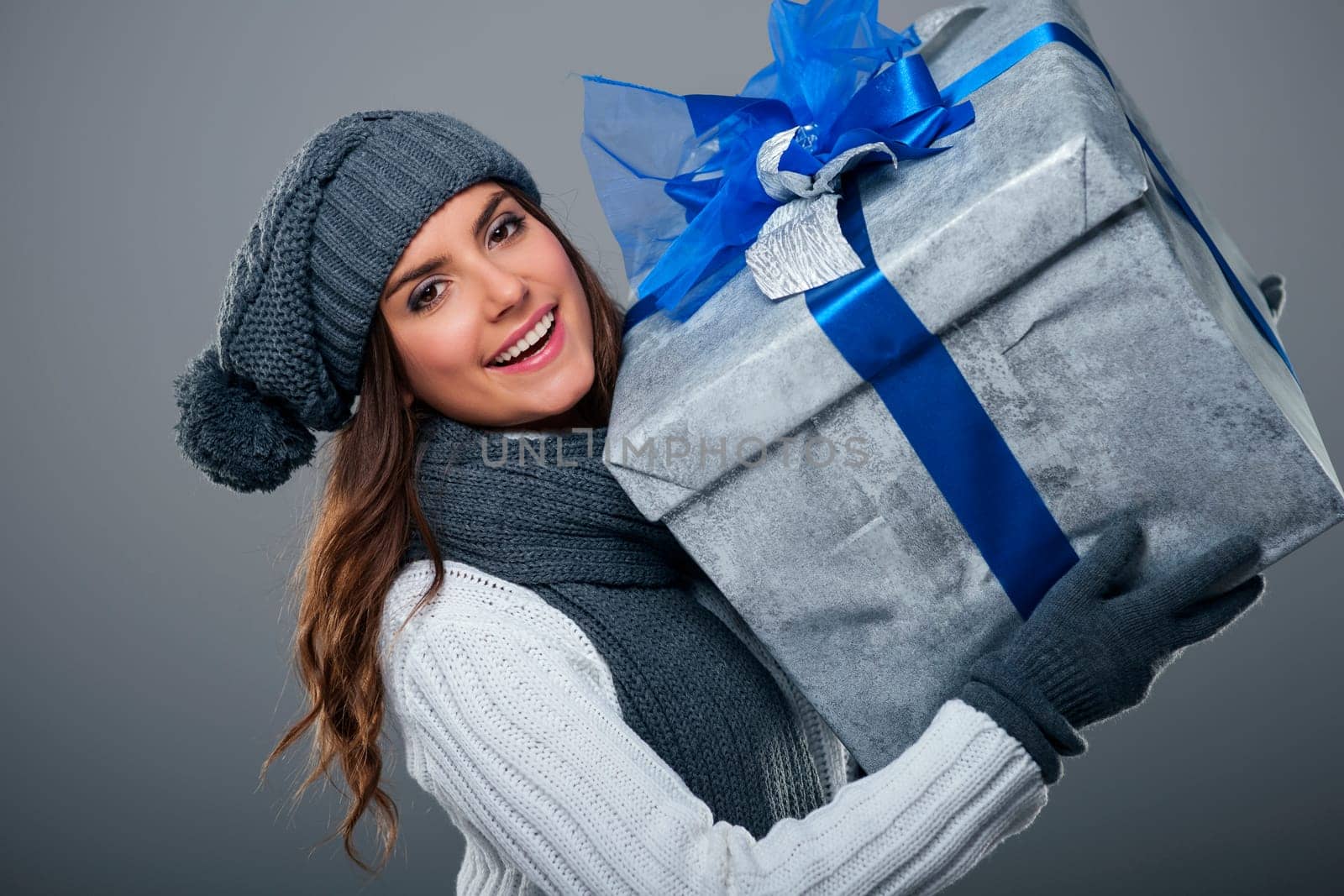 Happy woman wearing warm clothing holding big present