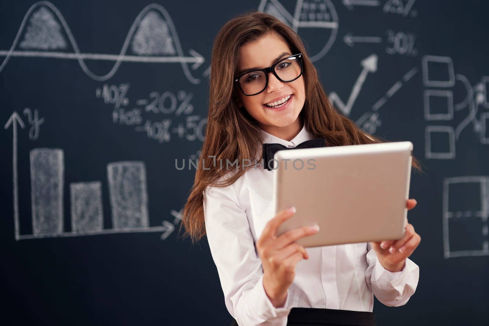 Smiling  teacher using digital tablet in classroom