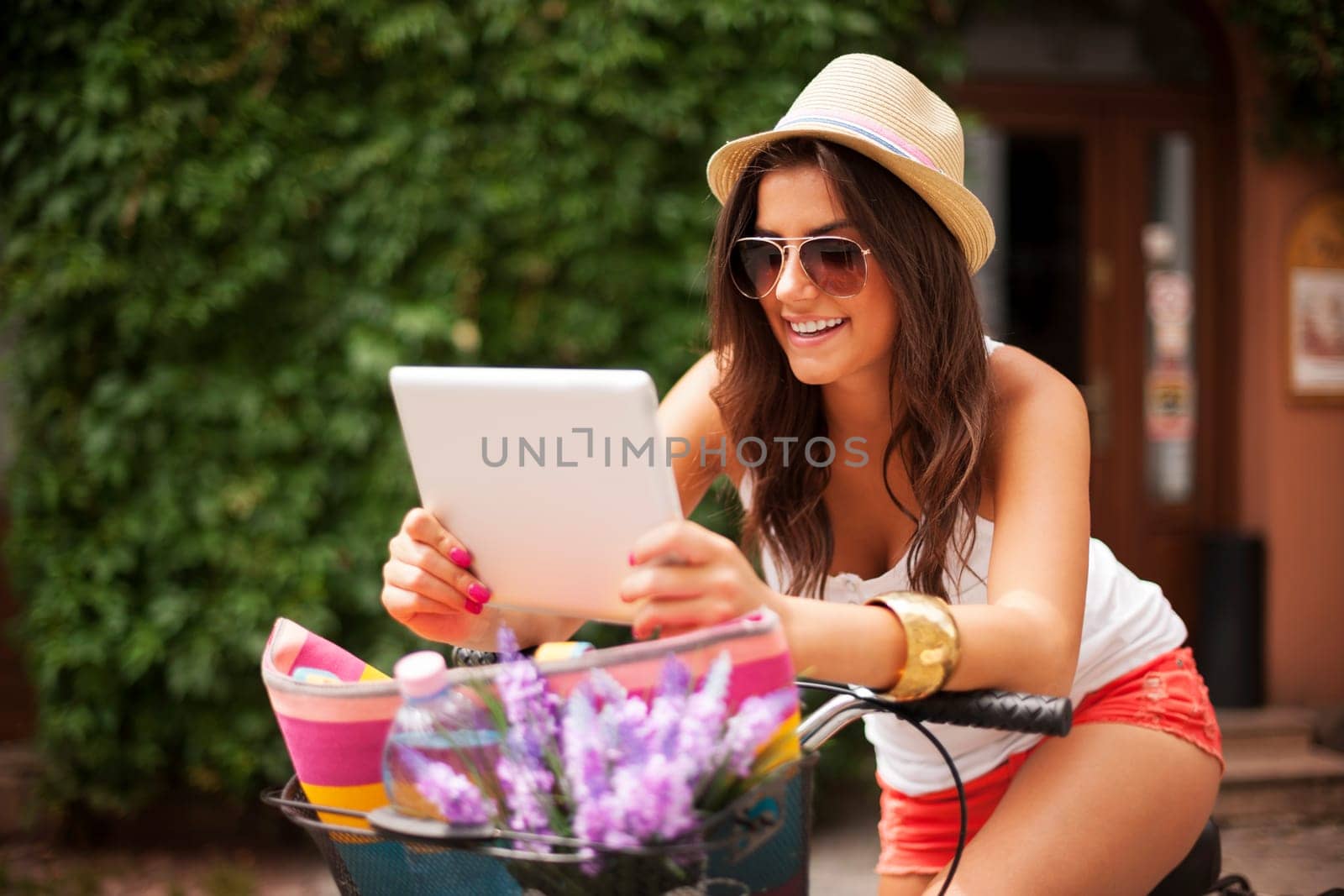Woman leaning on bike and checking something on tablet