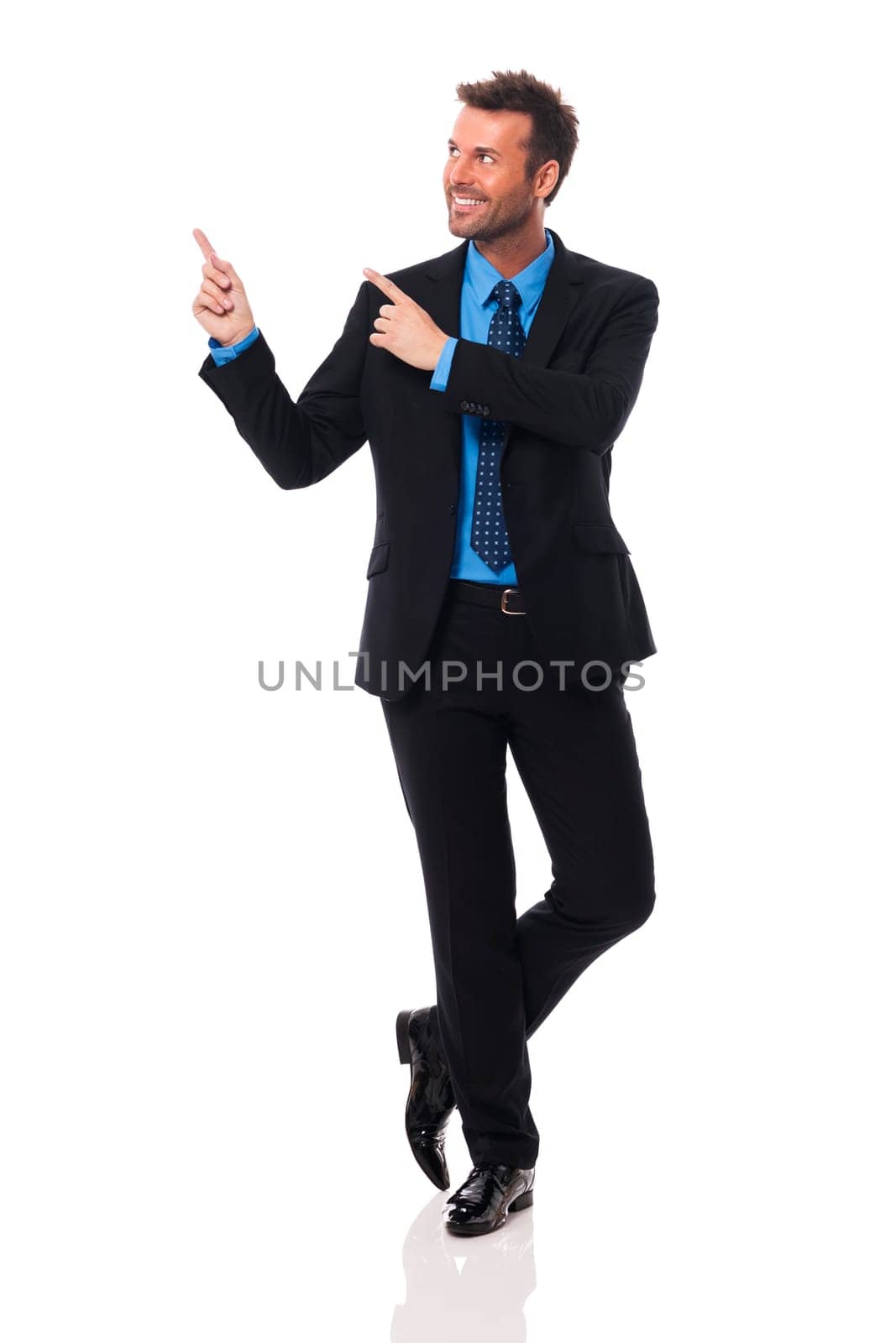 Handsome and smiling businessman pointing at copy space