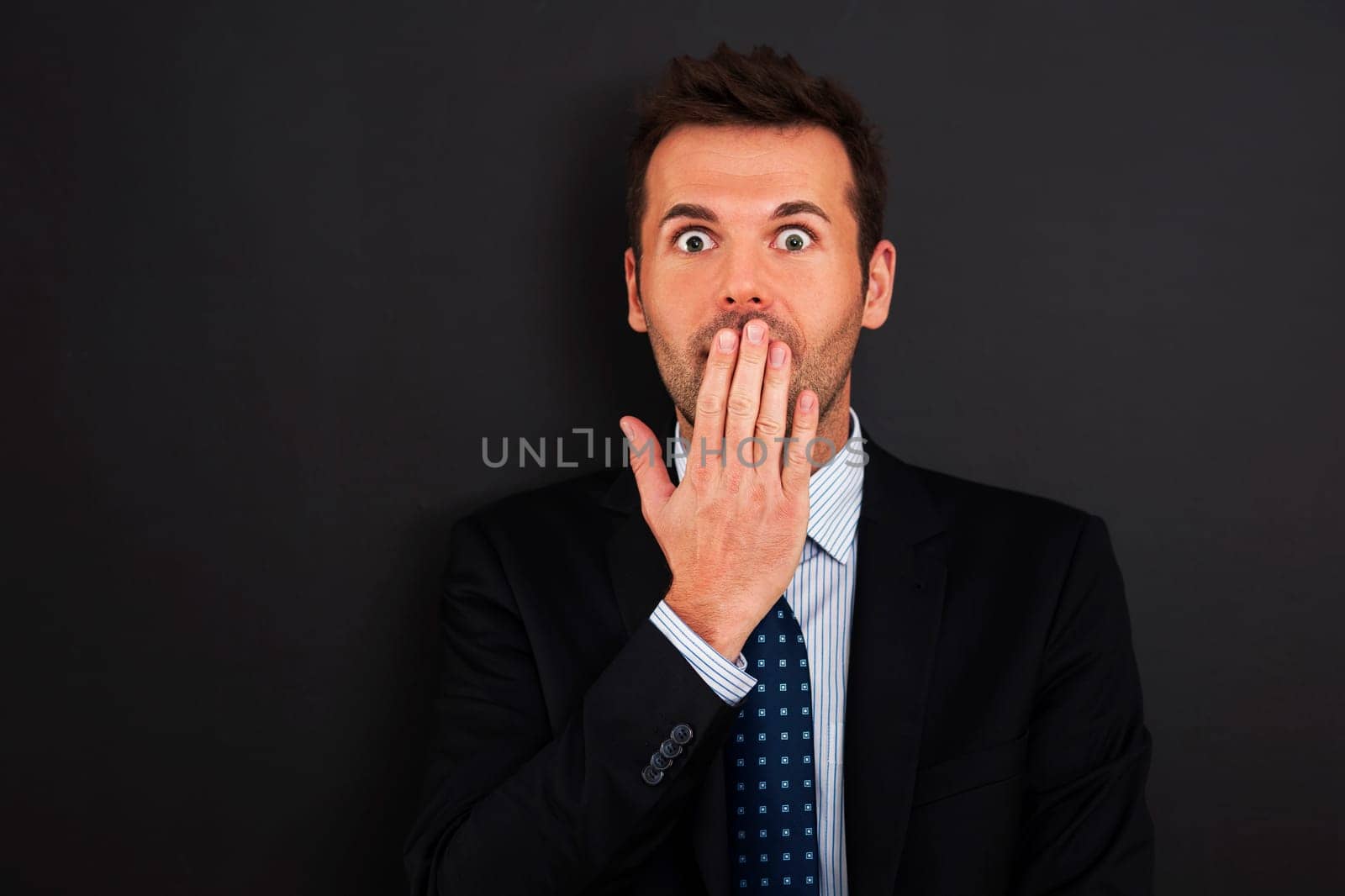 Fearful businessman covering his mouth