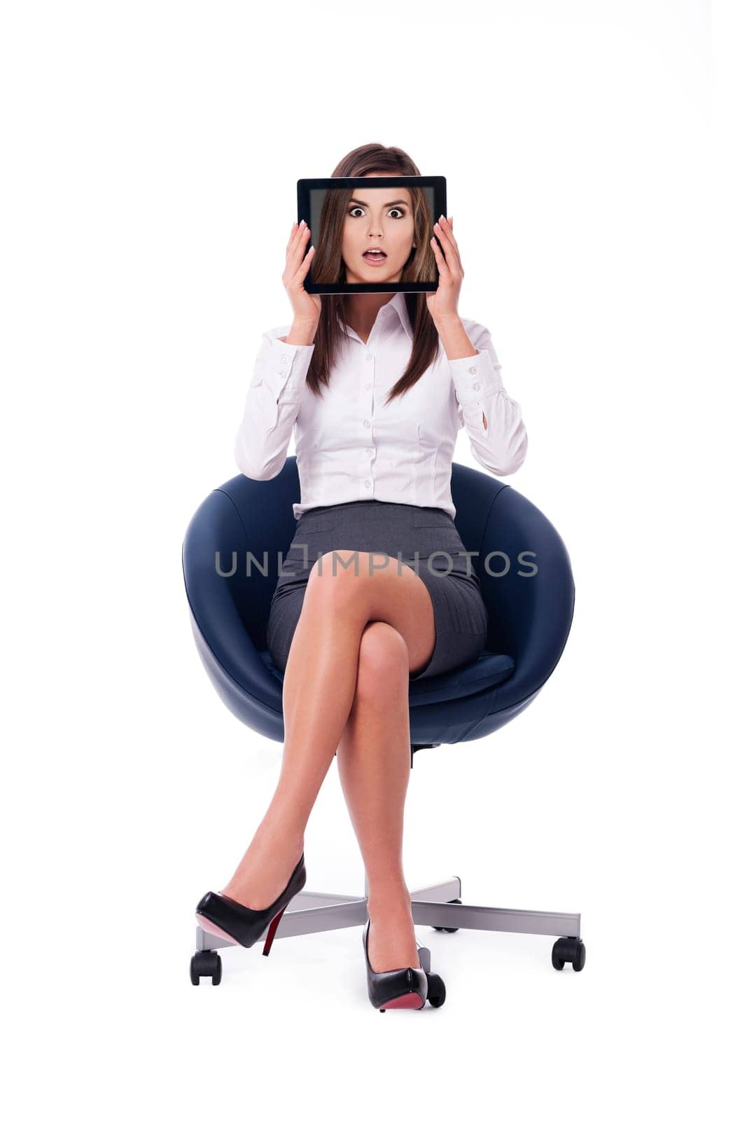 Businesswoman hiding behind tablet which displays shocked face