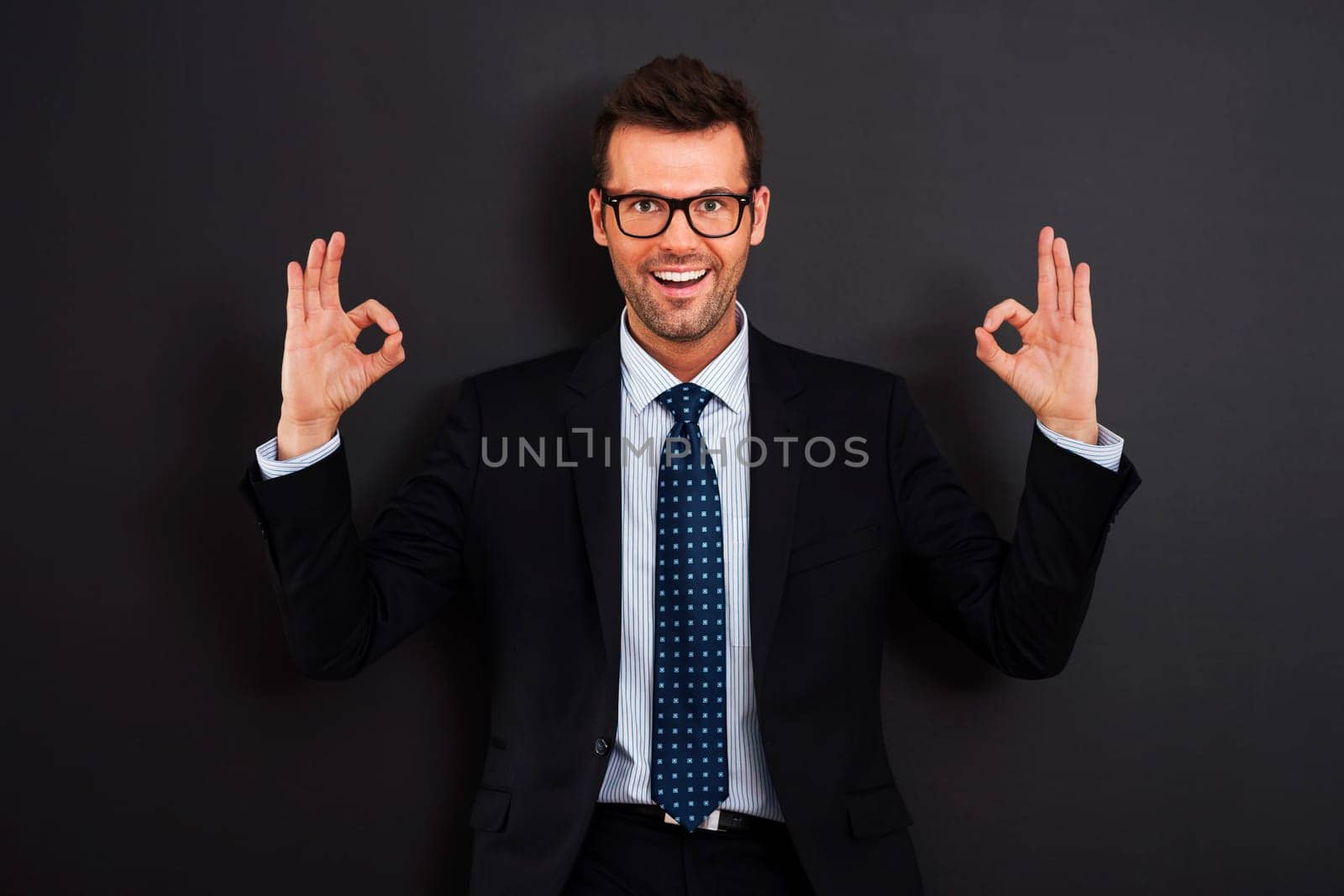 Happy businessman wearing glasses showing OK sign