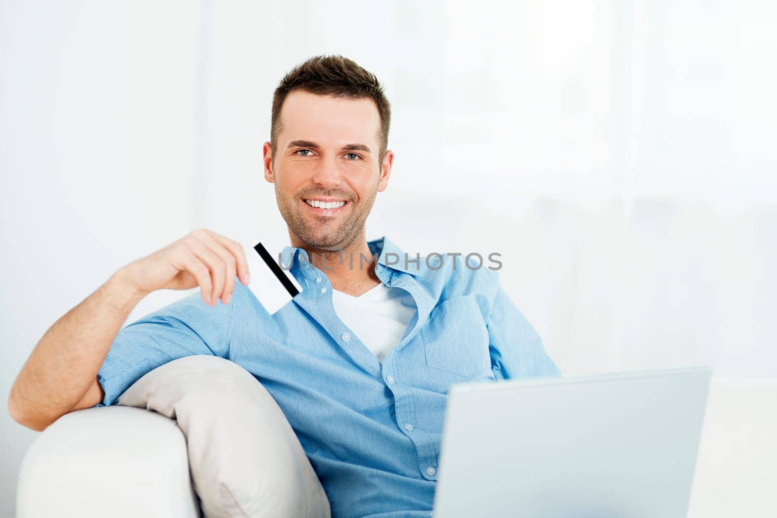 Handsome man holding credit card and using laptop