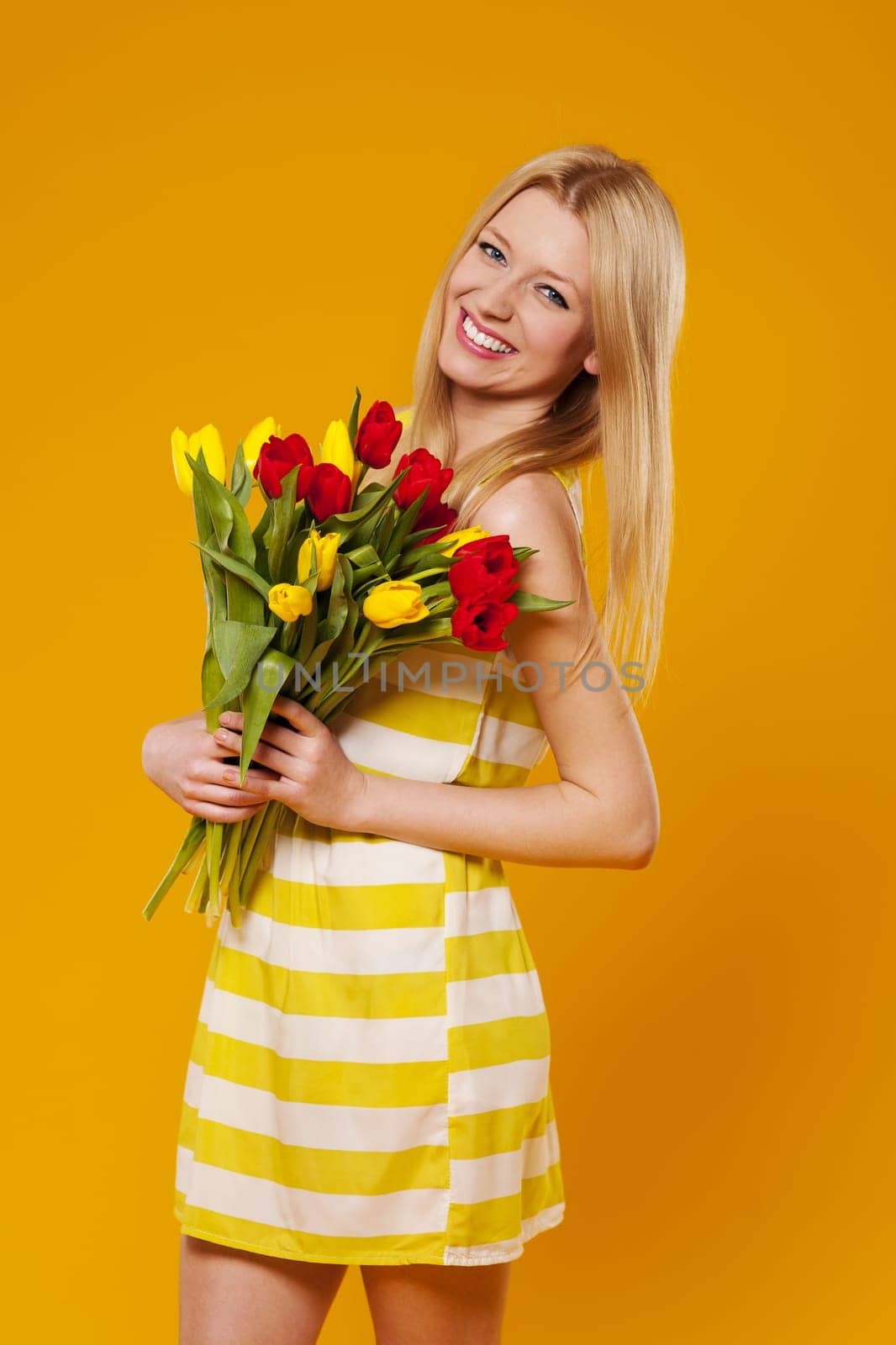 Young woman wearing in sundress with bouquet of tulips