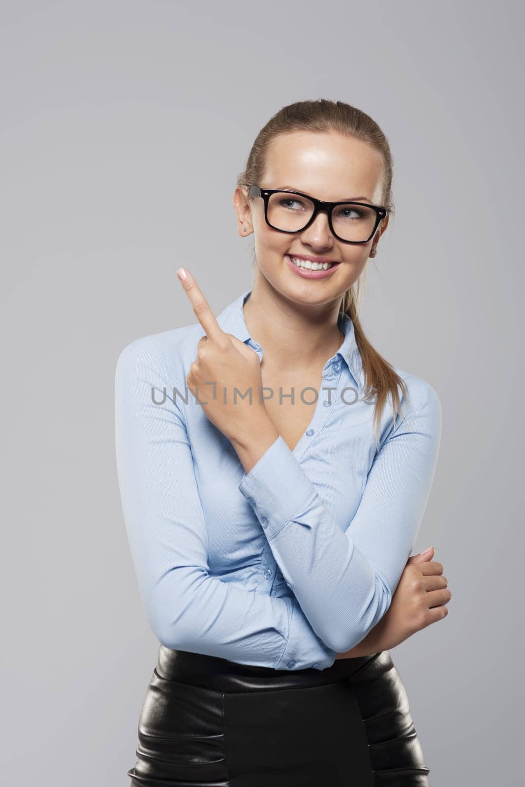 Happy young businesswoman pointing her finger on copy space