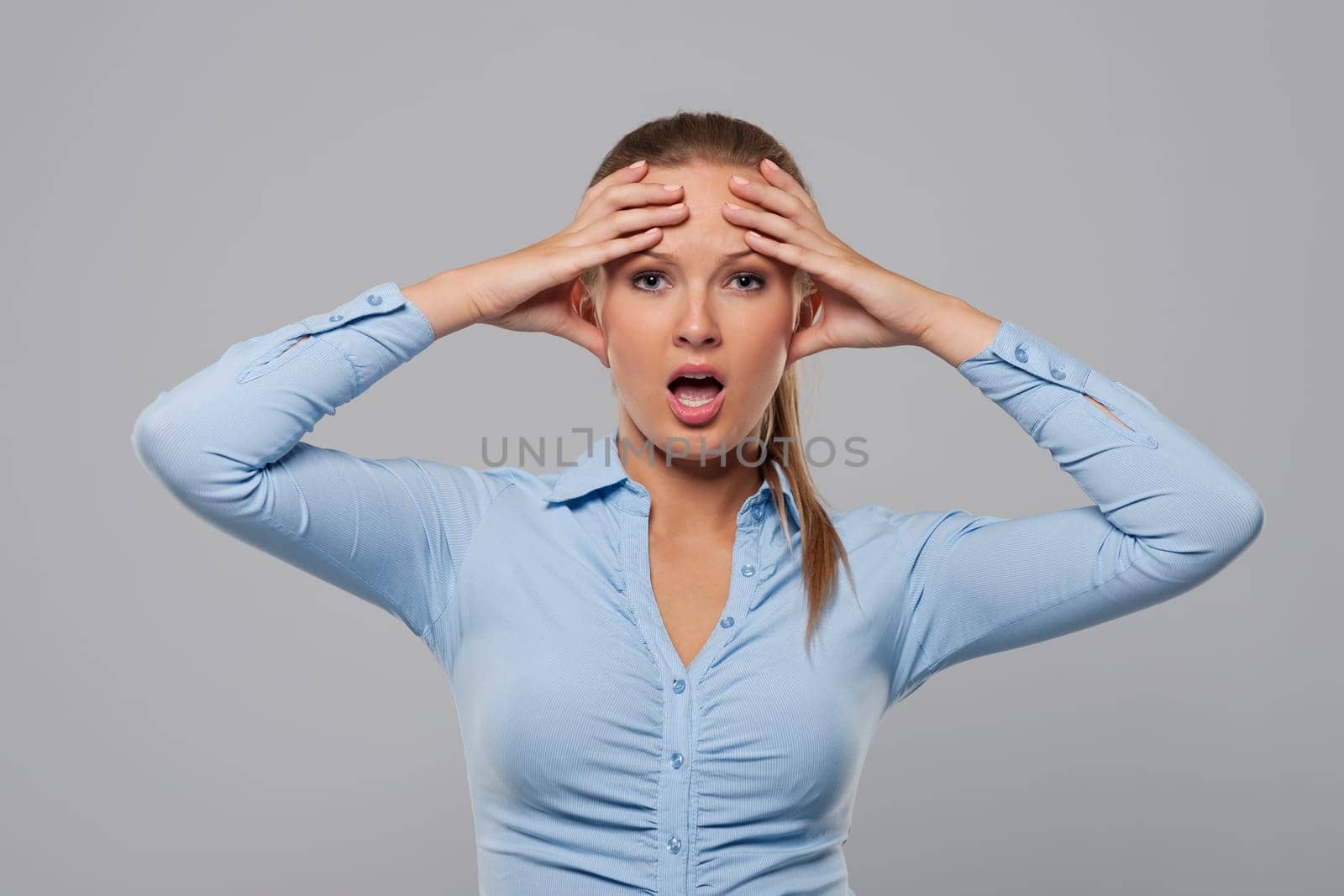 Confused and shocked businesswoman holding hands on head