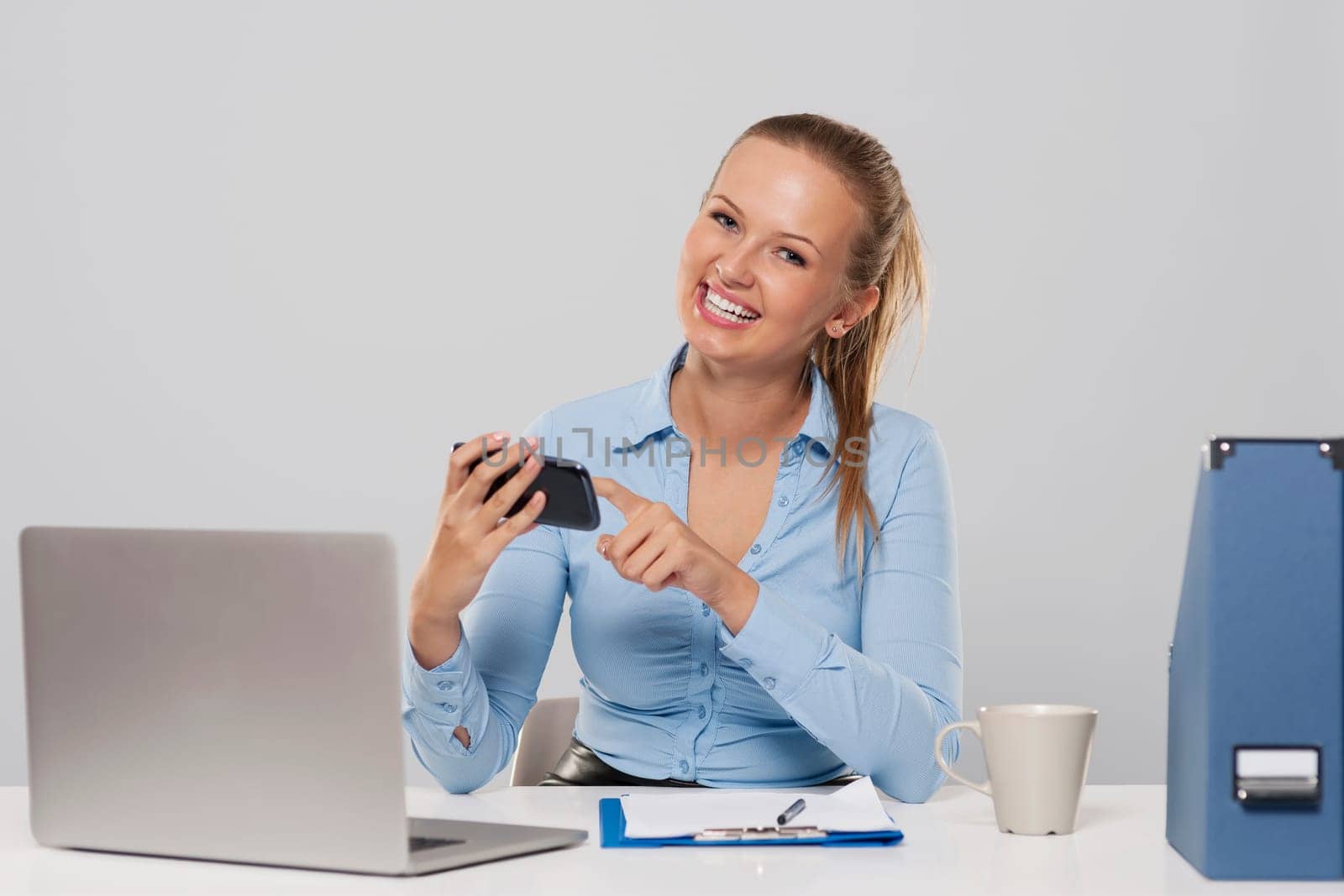 Cheerful beautiful and young businesswoman text messaging