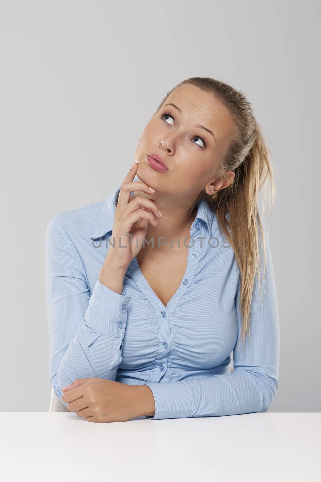 Thinking and pensive woman sitting at white desk