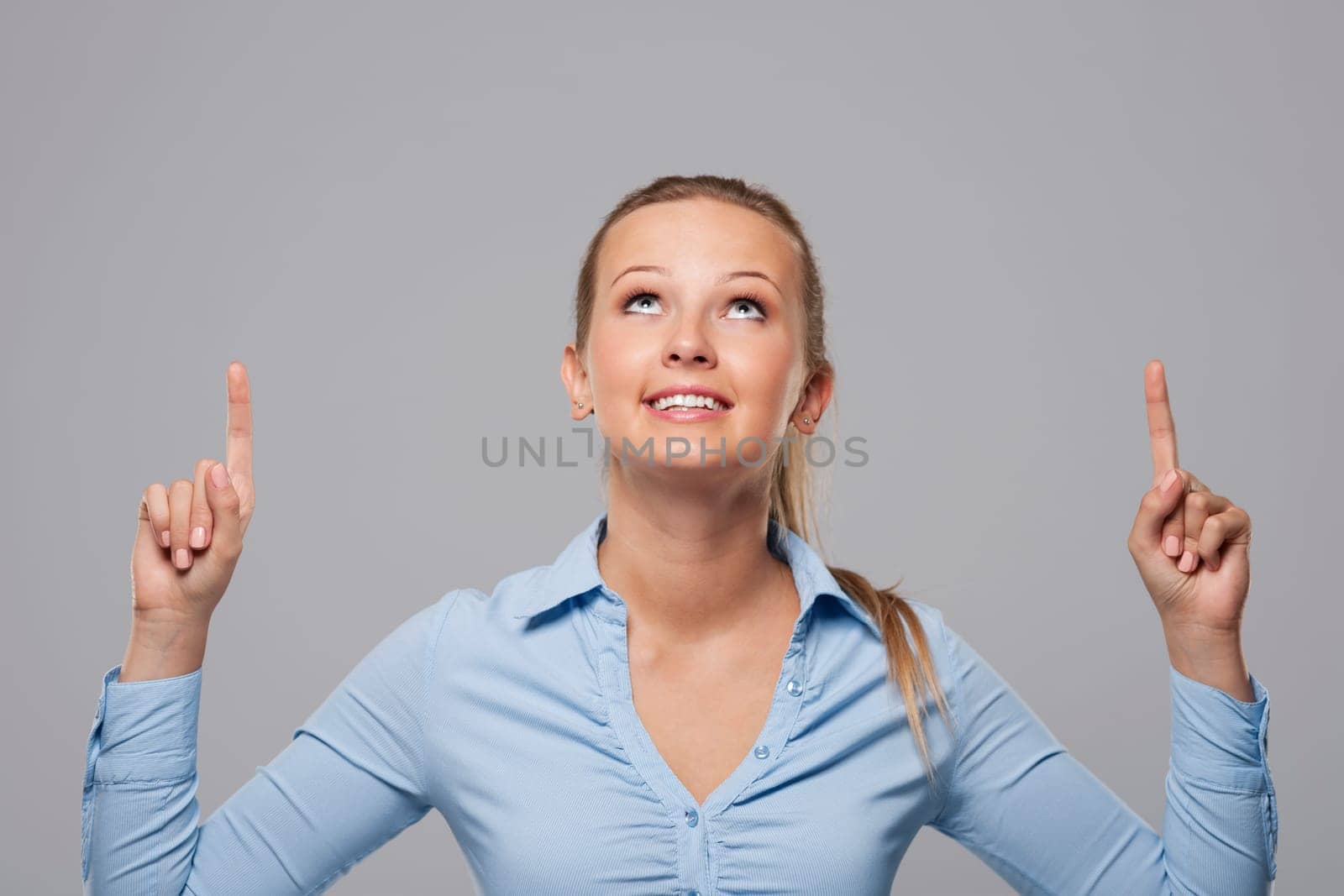 Blonde businesswoman pointing above at copy space