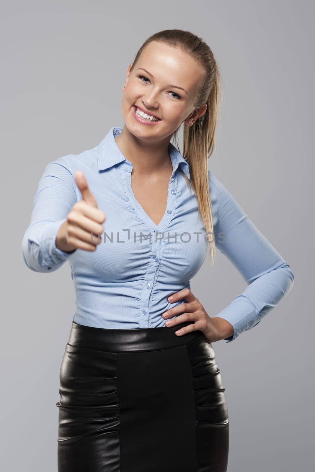 Smiling young businesswoman showing thumb up