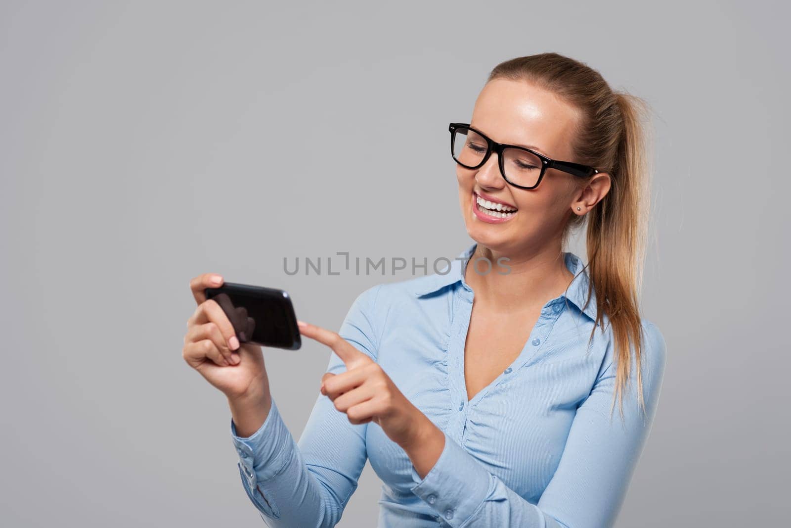 Smiling woman with glasses using mobile phone