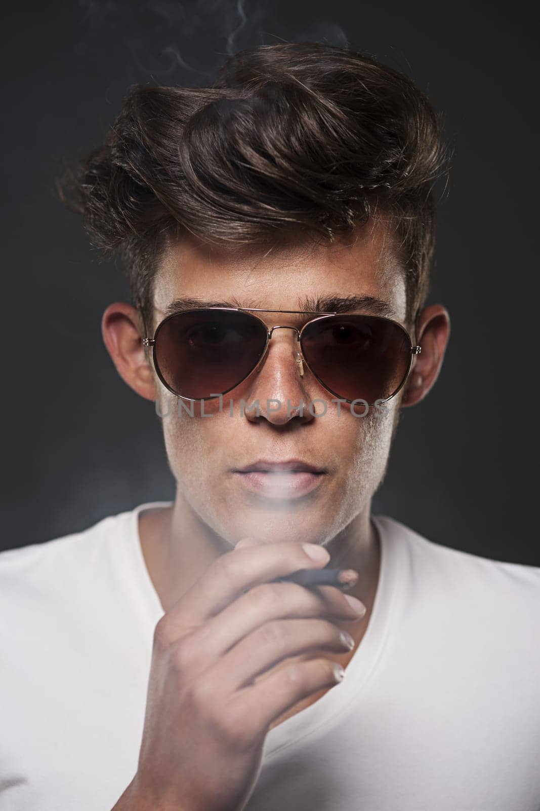 Fashionable young man exhaling cigarette smoke