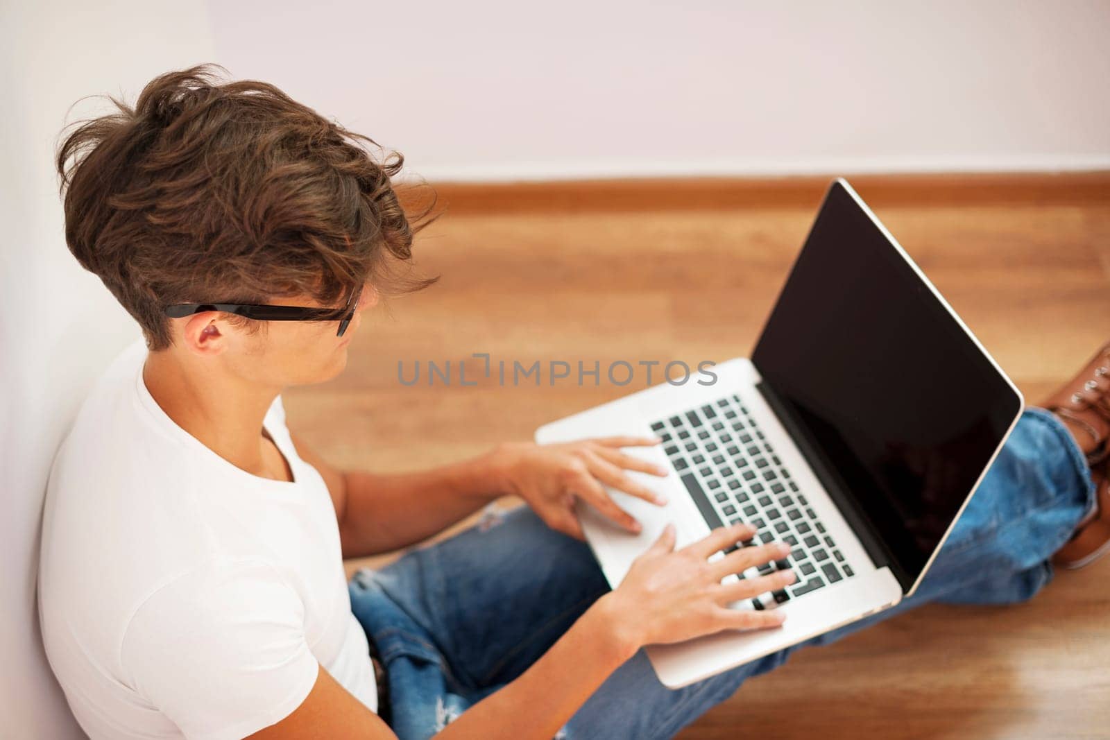 Young man looking thoughtful and using laptop