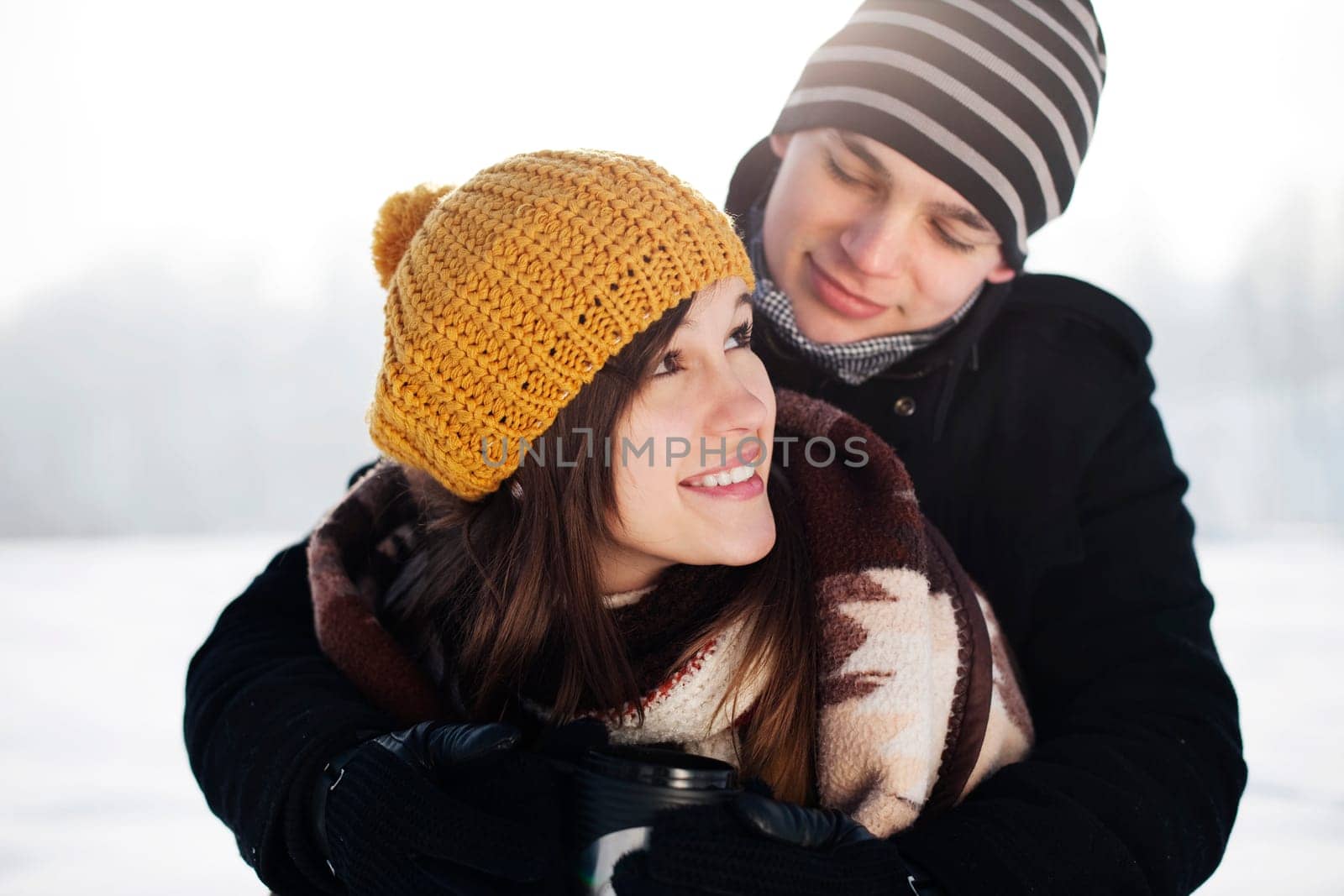 Young man wrapping his girlfriend into blanket
