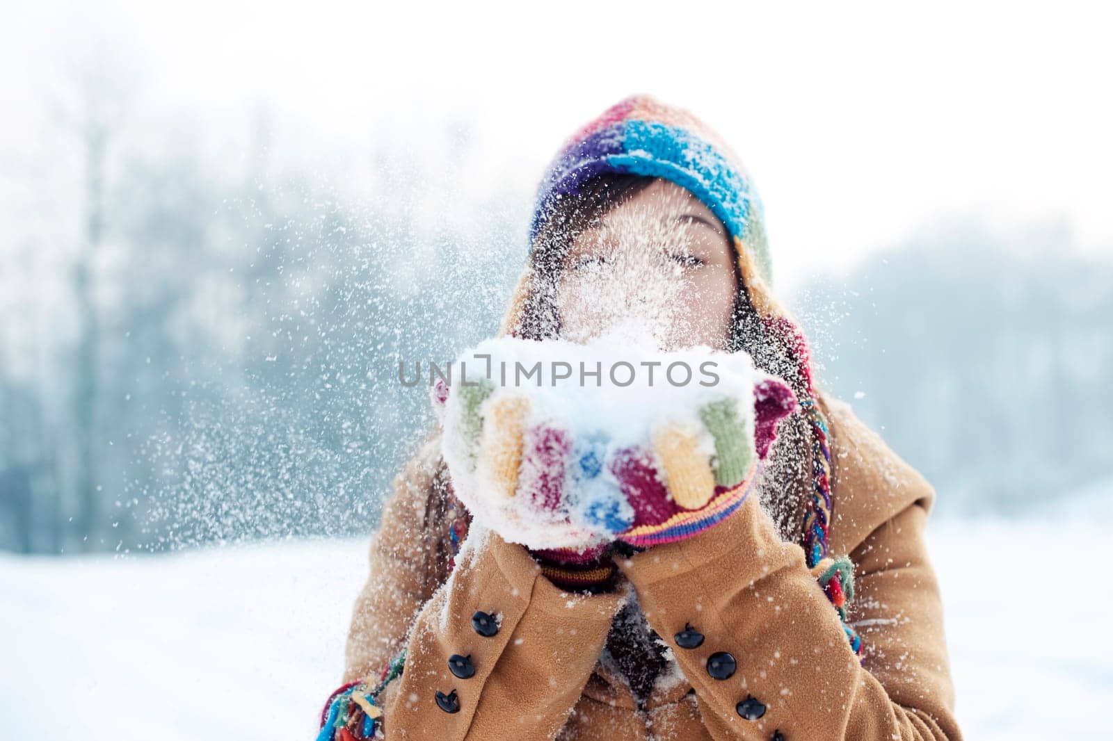 Young woman blowing snow to away