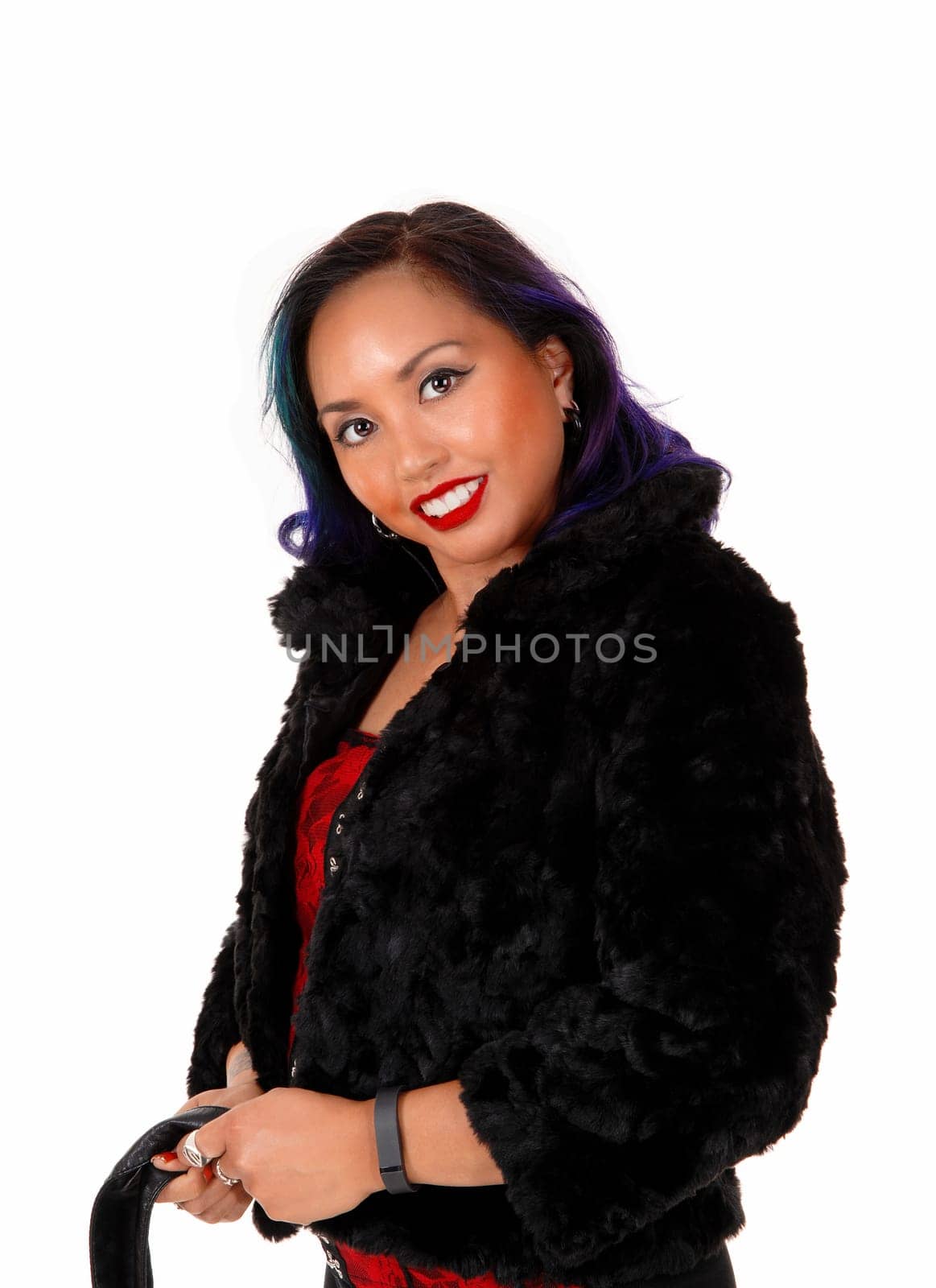 A pretty Asian woman in a red corset and black jacket standing for white.background looking serious..