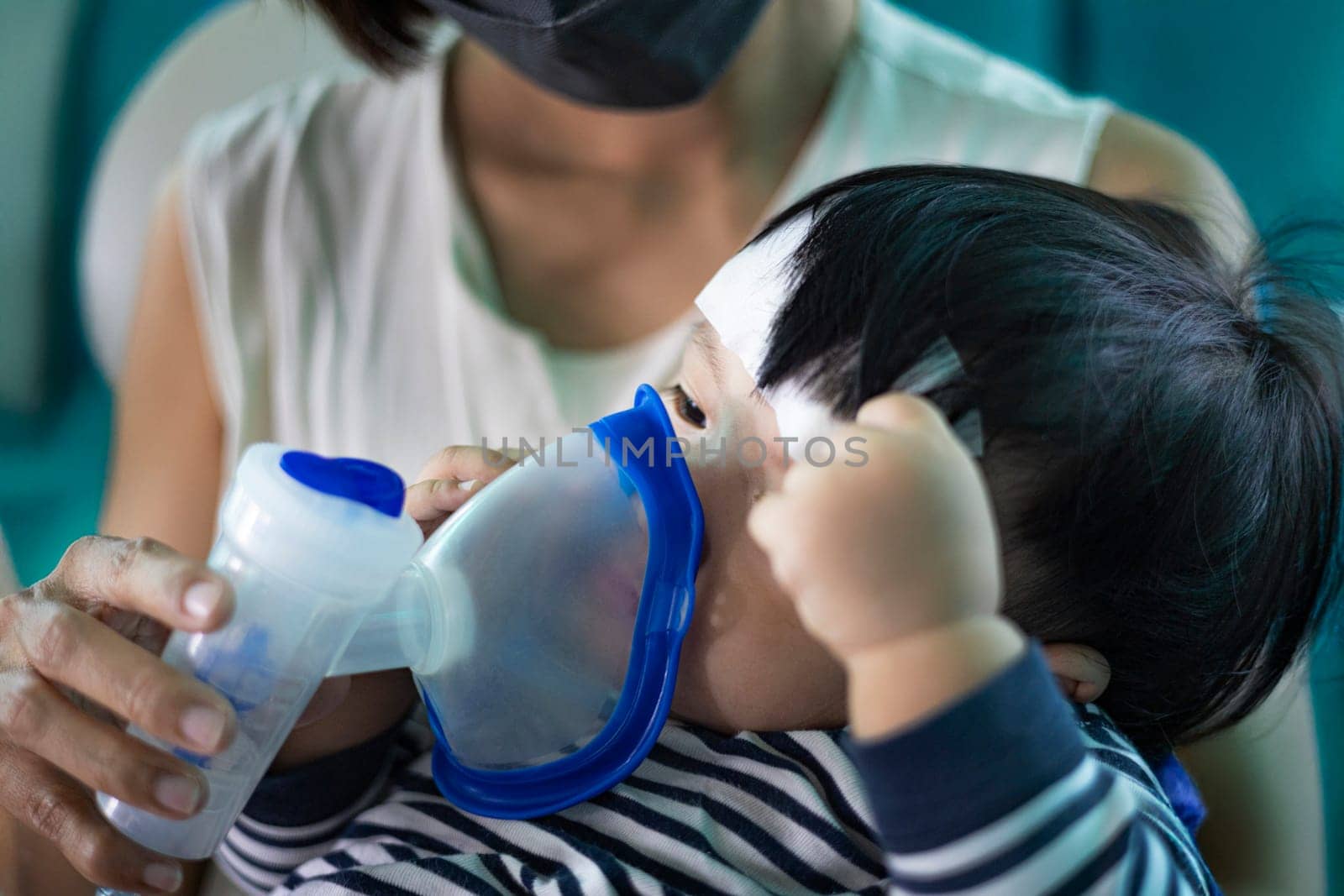 Mother helps her son doing inhalation with a nebulizer. Using nebulizer and inhaler for the treatment.