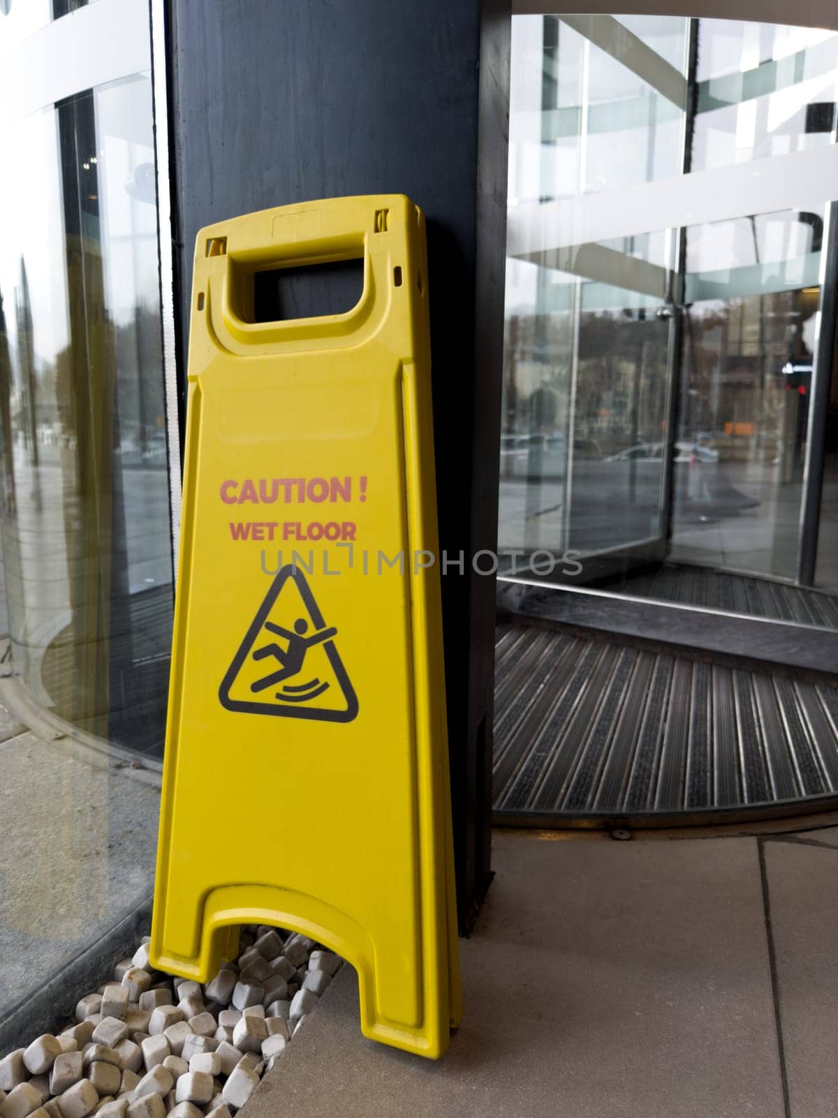 Vertical photograph of wet floor warning sign. Yellow fold out sign to alert people for safety that floors have been washed. Don't fall on slippery floor. Caution wet floor