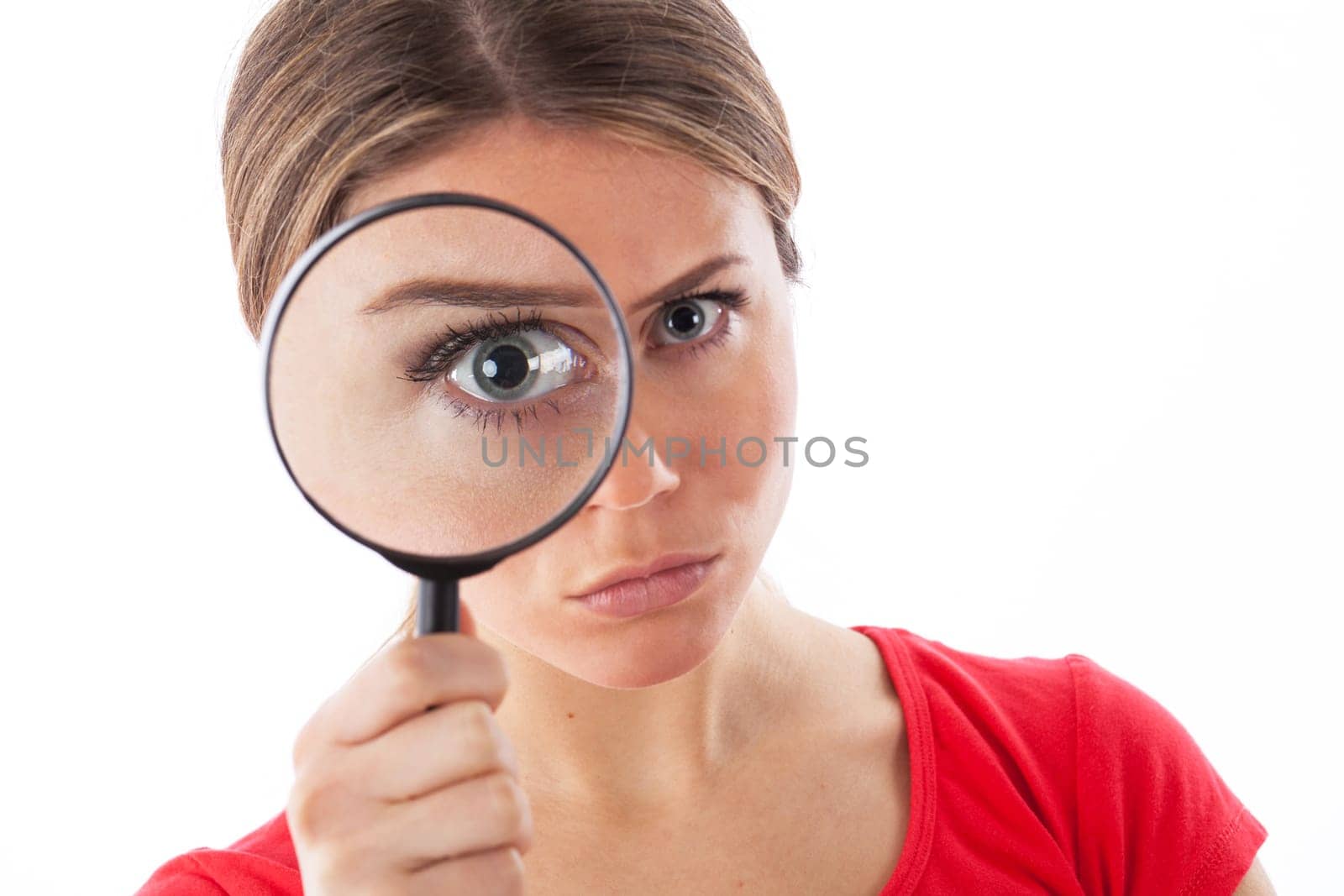 Cute woman looking through a magnifying glass, isolated on white