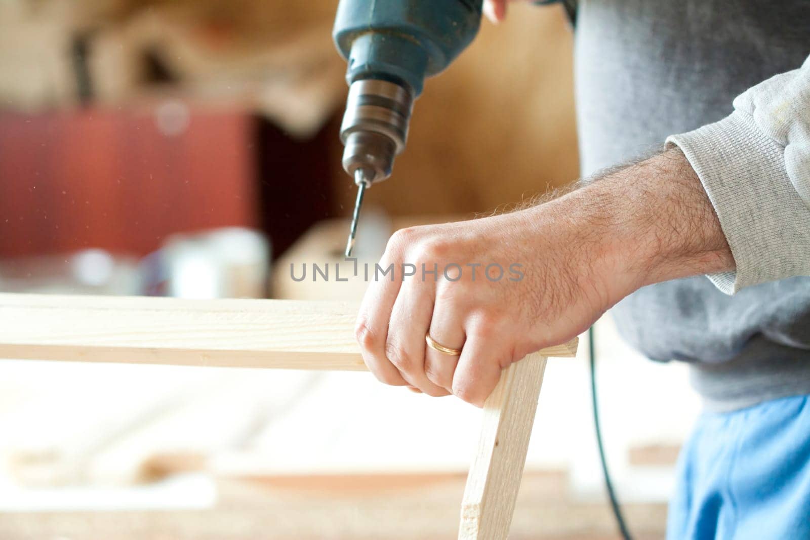 Man's arms drill lath in the workshop.