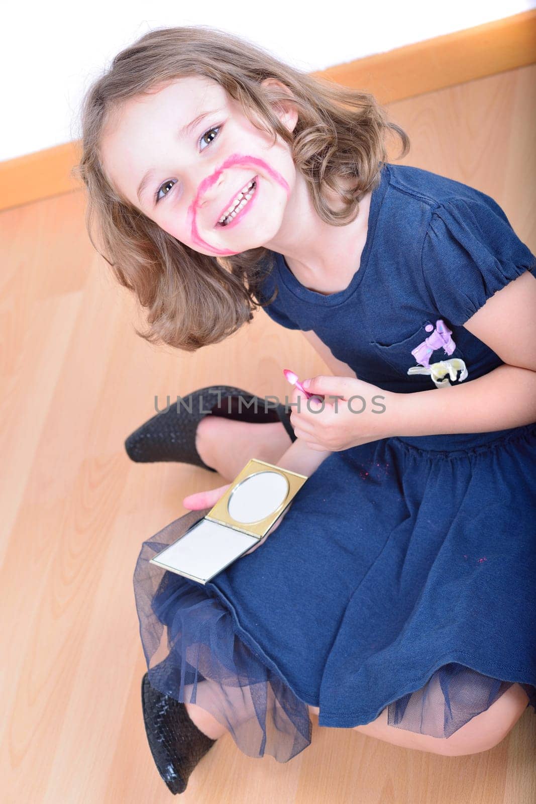 Little cute girl using make-up to turn herself into clown