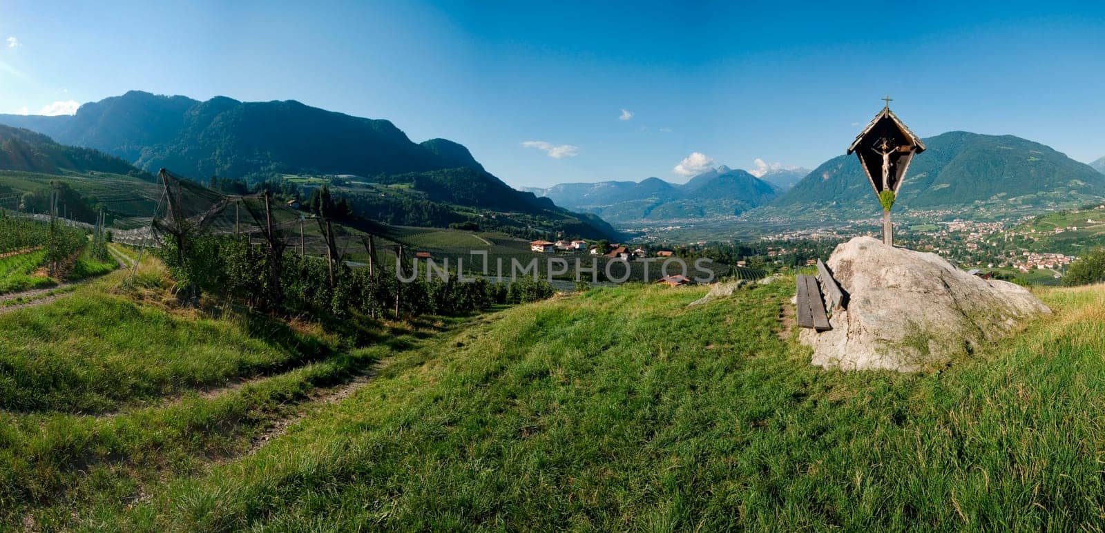 Panoramic view above the city of Merano / South Tyrol with cross between apple plantations and view of the opposite Texel Group