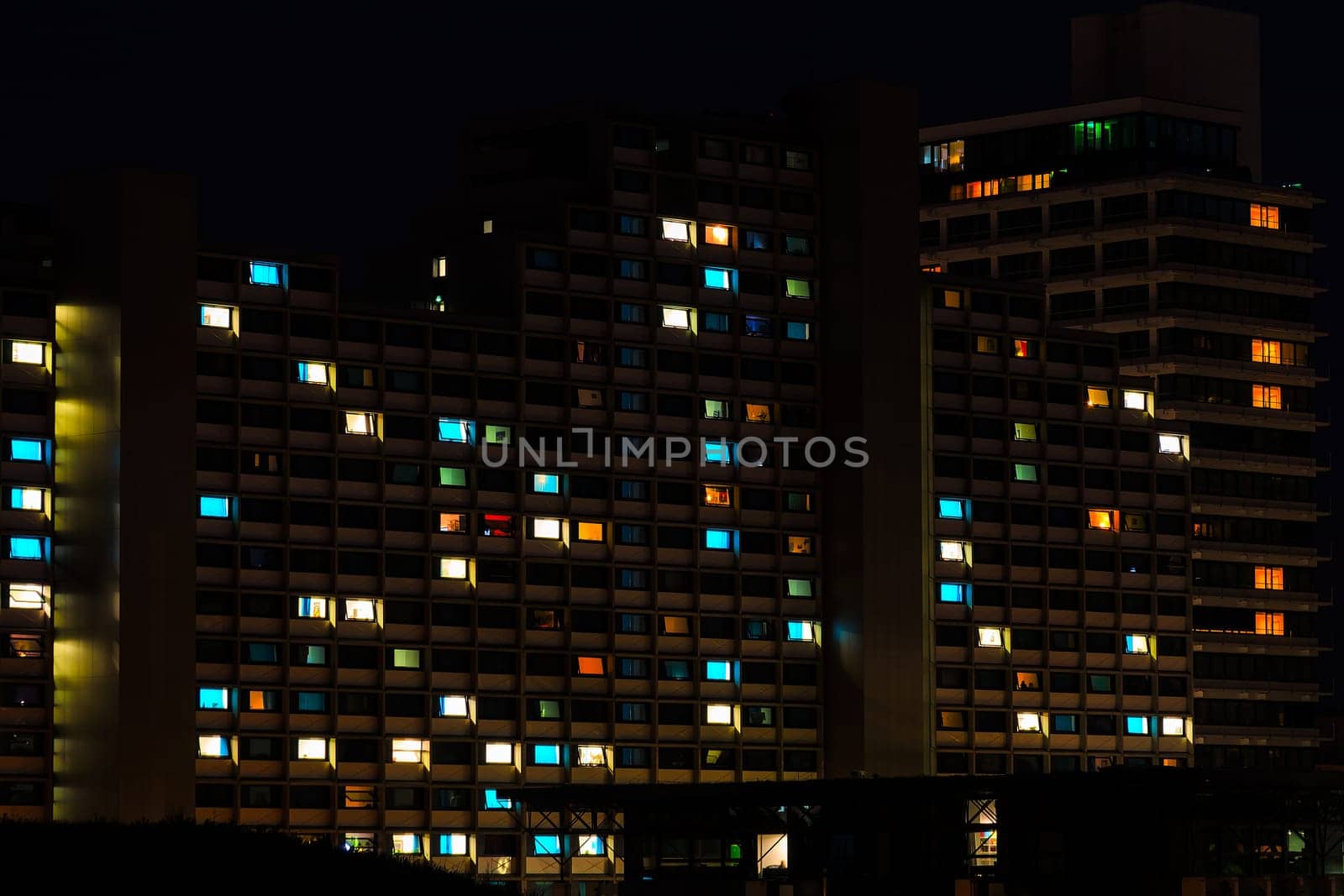 Night colorful windows lights of the high-rise residential building in city sleeping area