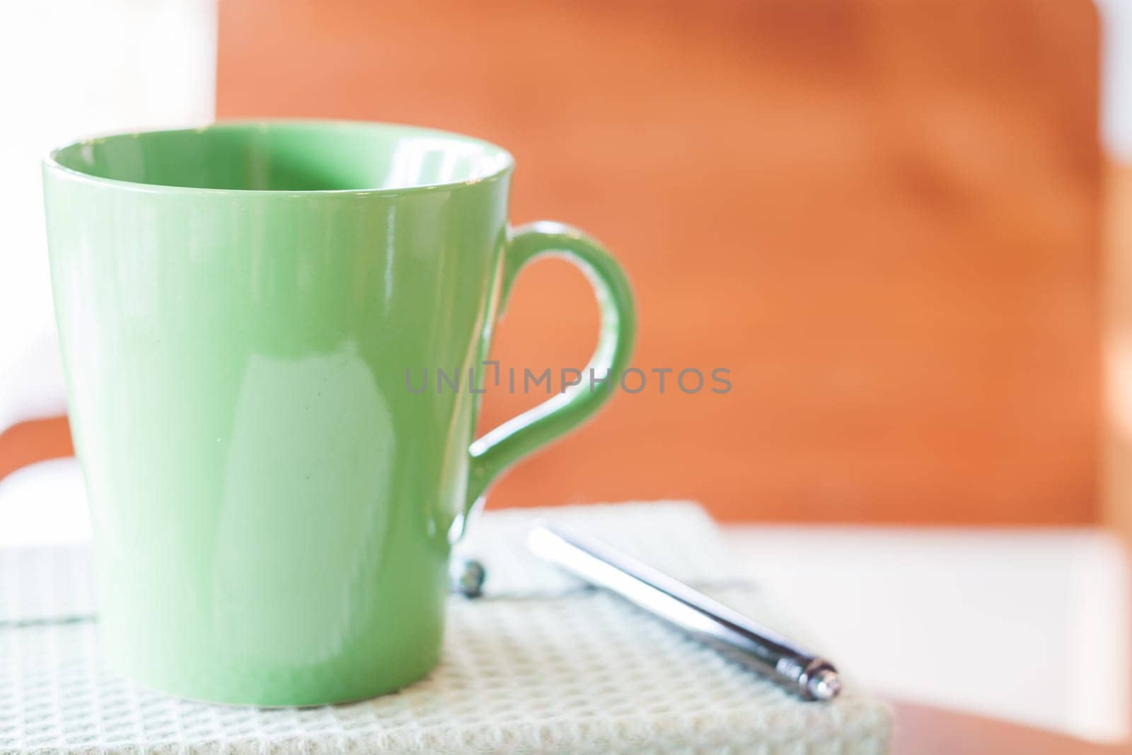 Closeup green mug with pen and notebook, stock photo