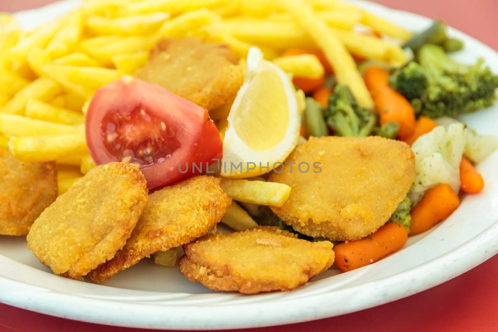 Fried chicken nuggets, French fries, lemon and vegetables
