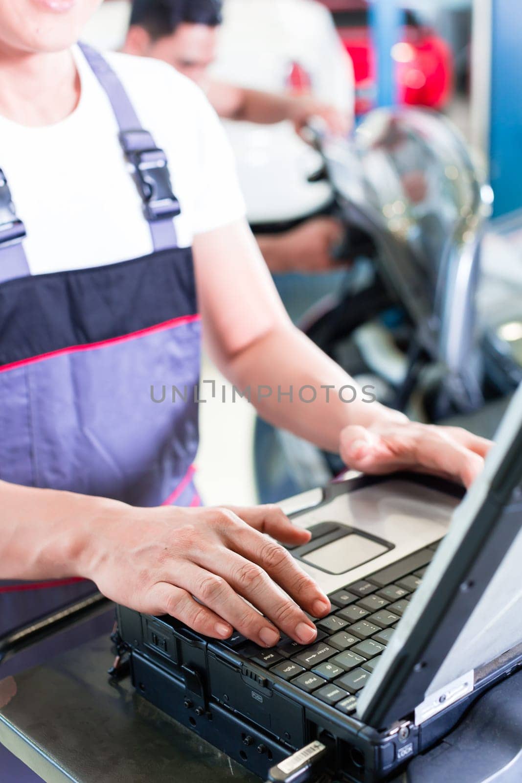 car mechanic checking auto engine with diagnostics tool in his workshop
