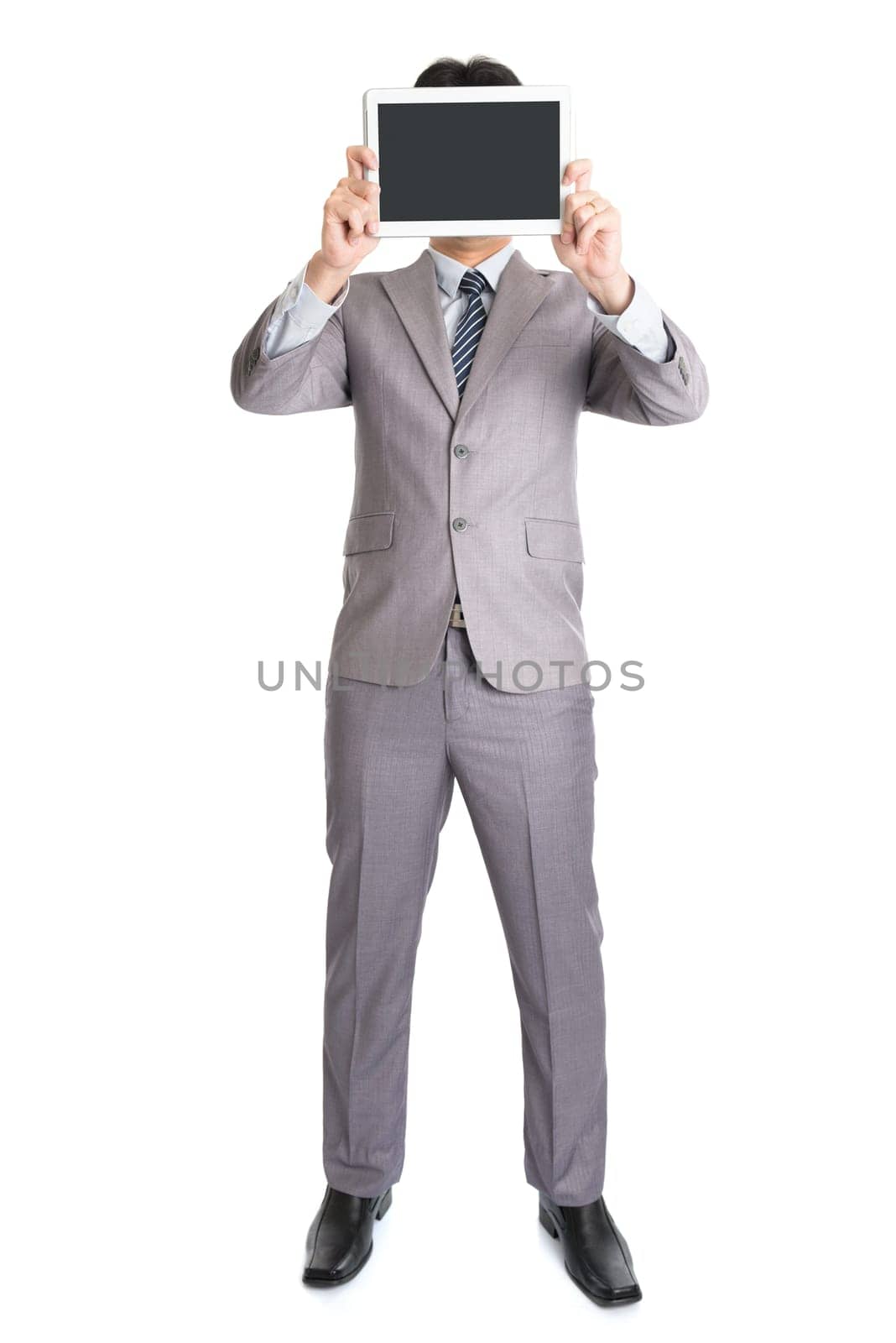 Full body Asian businessman hand holding digital computer tablet covering his face, standing isolated on white background.