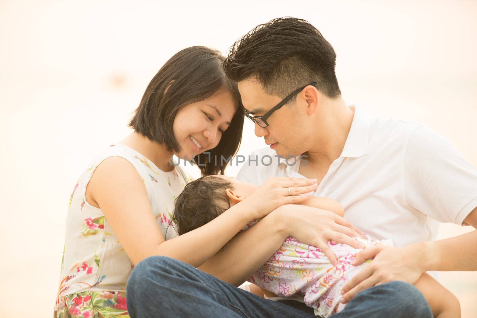 Asian Chinese family seated on beach outdoor, vacation during summer, natural sunset sunlight