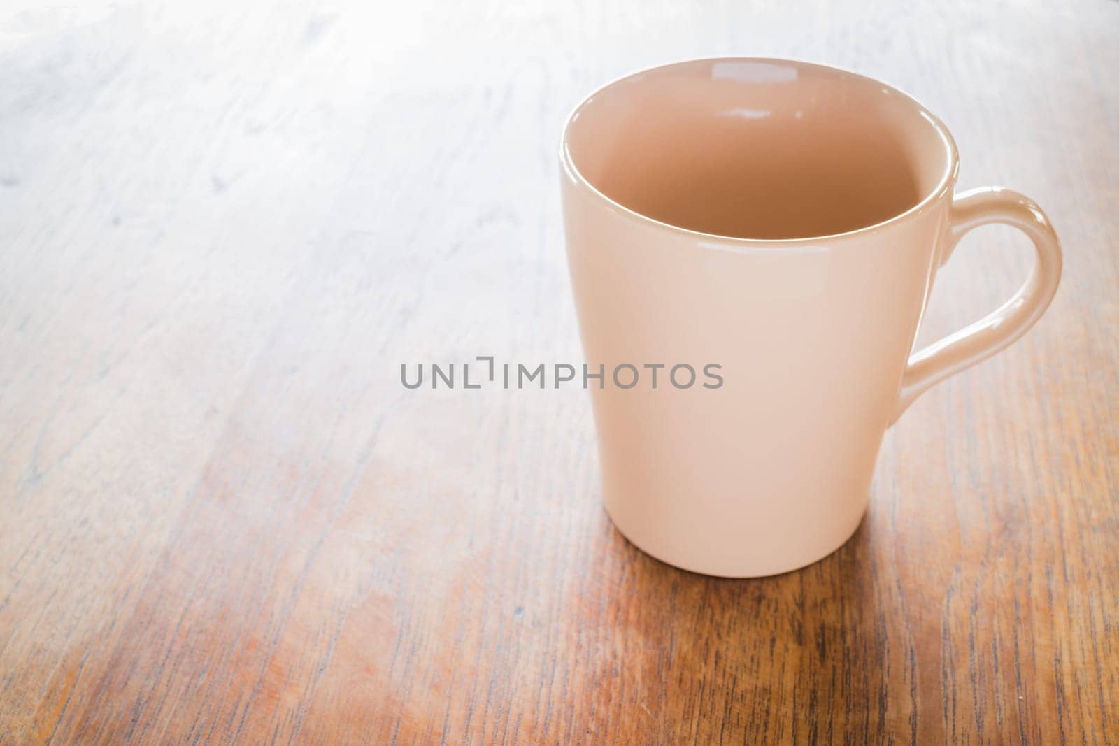 Brown ceramic cup on wooden table, stock photo