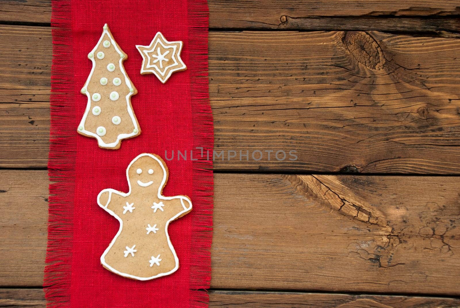 A Ginger Bread Woman, Christmas Tree and Star on Red Drapery on Wooden Background with Copy Space