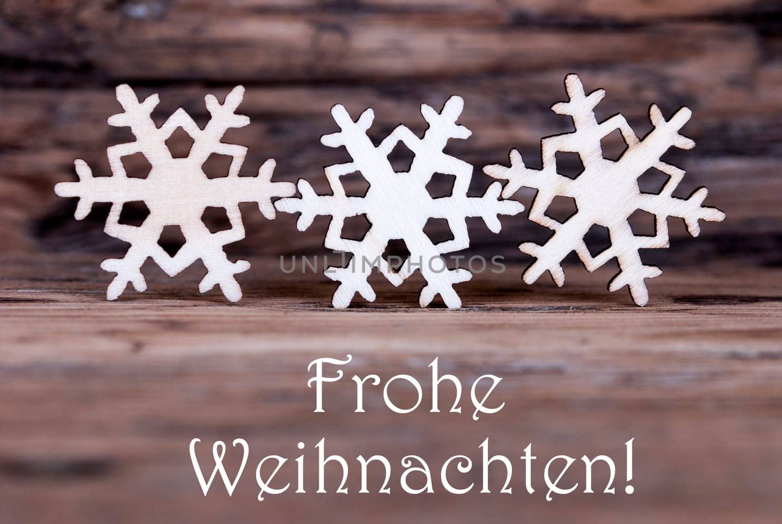 Three Wooden Snowflakes with the German Words Frohe Weihnachten which means Merry Christmas