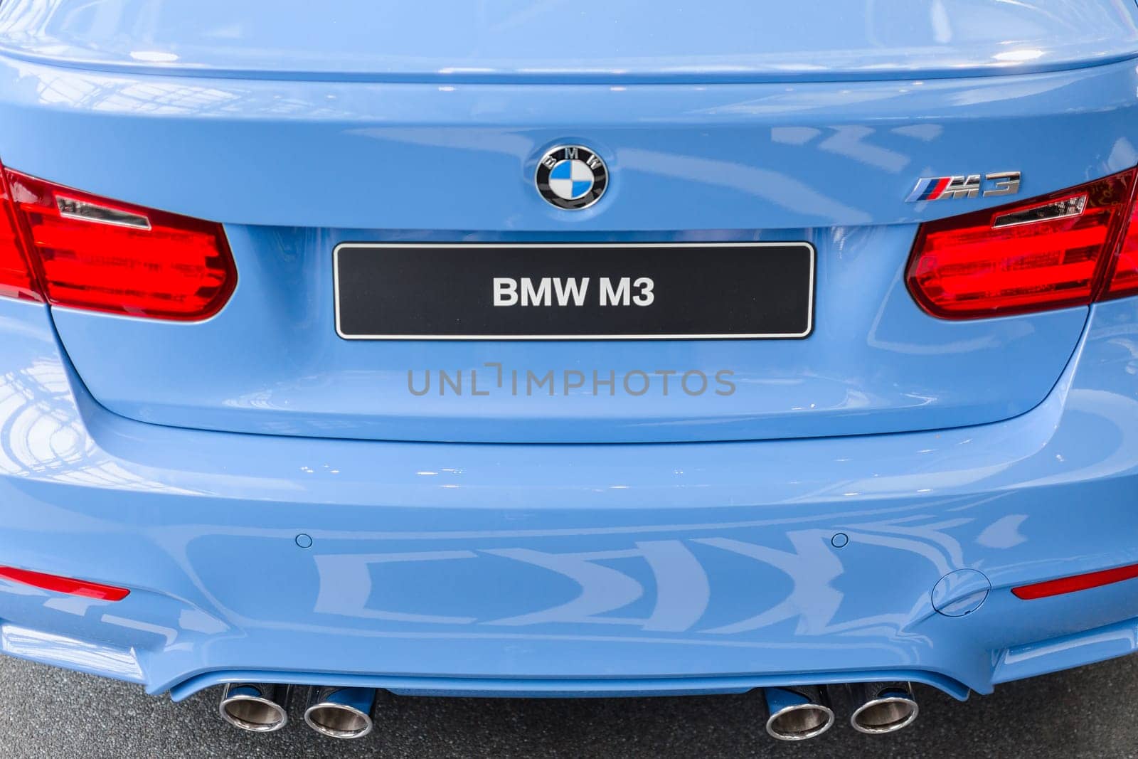 Rear view of new generation model BMW M3 - prestigious sports style car. Close-up details with chrome exhaust pipes and stop lights.