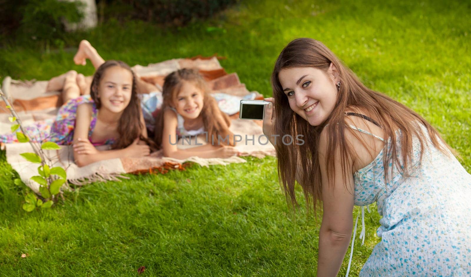 Happy mother and daughter making photos during picnic at park